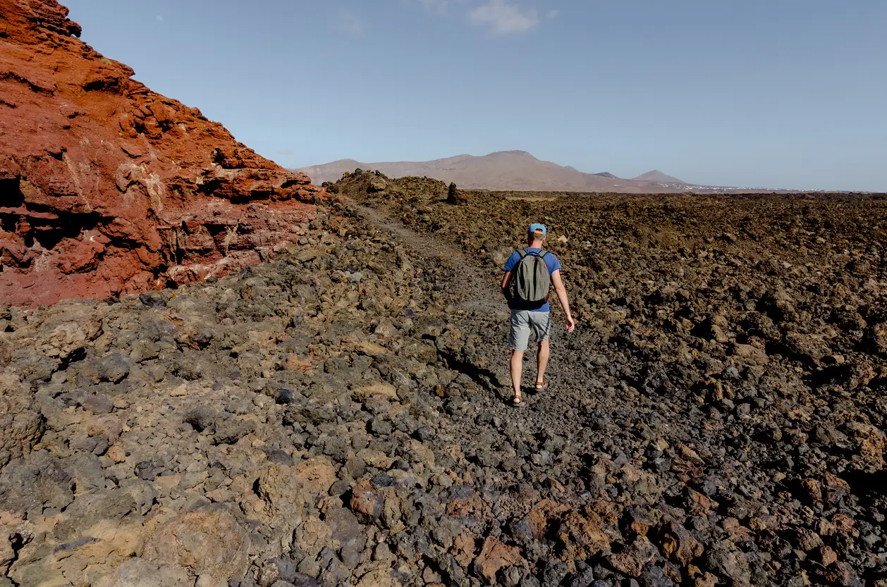Ein Mann in Vulkanlandschaft des Timanfaya trekking