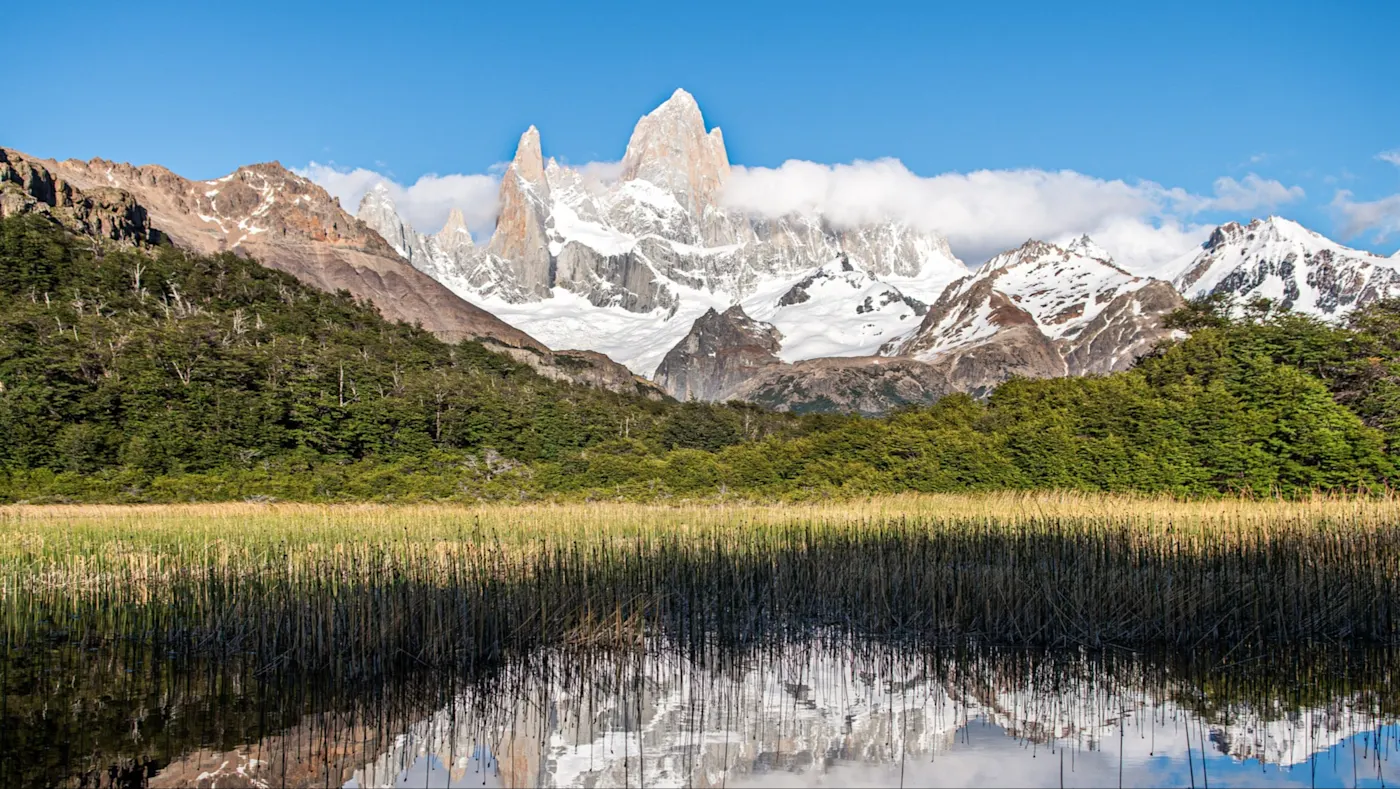 Argentinien, Patagonien, El Chaltén Schneebedeckte Berge mit Wäldern und Wasser im Vordergrund. El Chaltén, Patagonien, Argentinien.