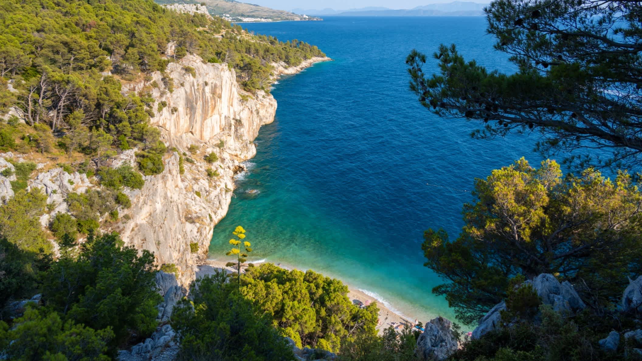 Der Strand von Nugal (Makarska), Tučepi, Kroatien mit Blick auf die Felssteilwände sowie dem Pinienwald und dem blauen Meer aus der Luft.