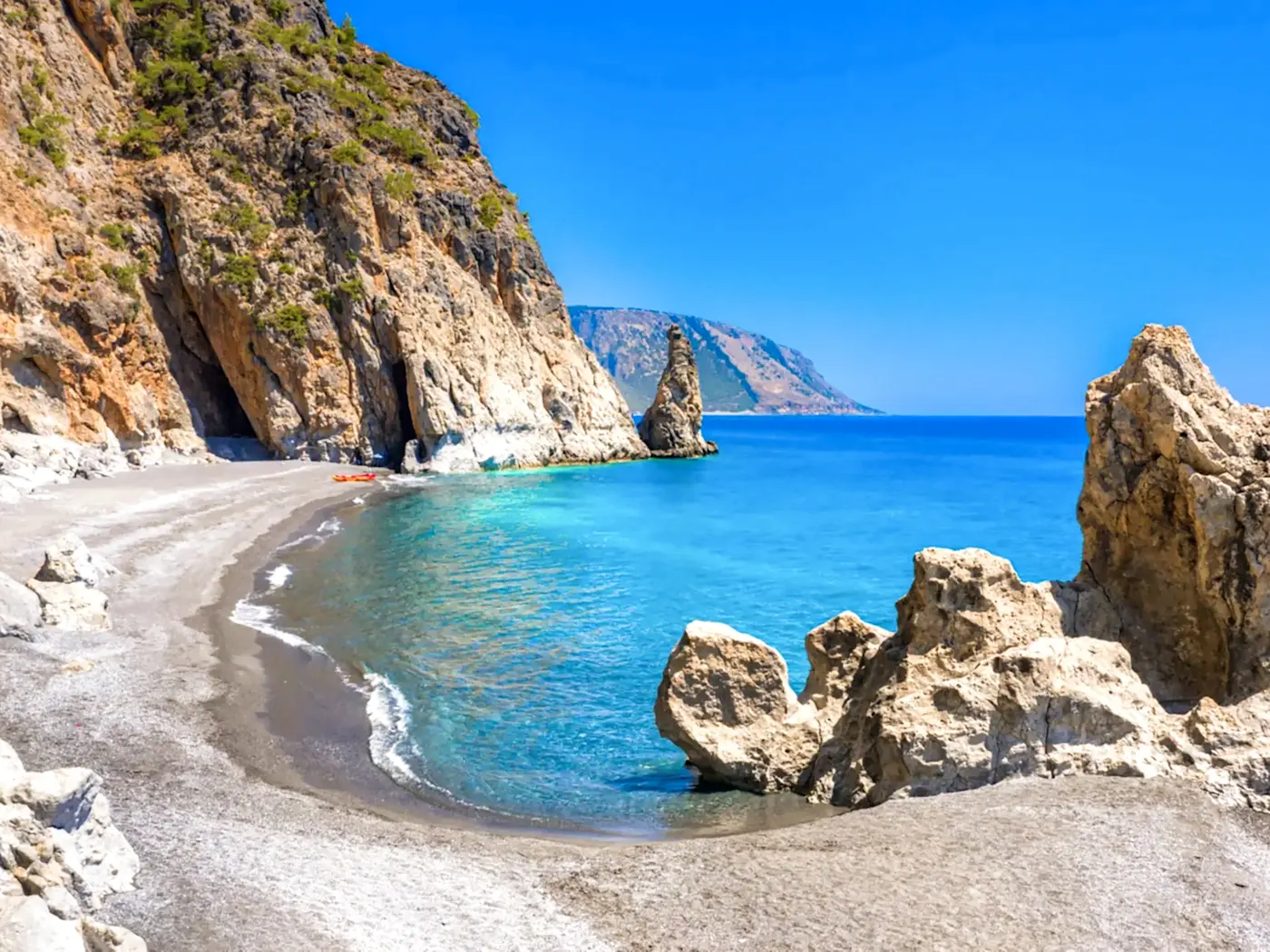 Felsige Küste mit klarem Wasser und Sandstrand. Kalogeros Strand, Paros, Kykladen, Griechenland.