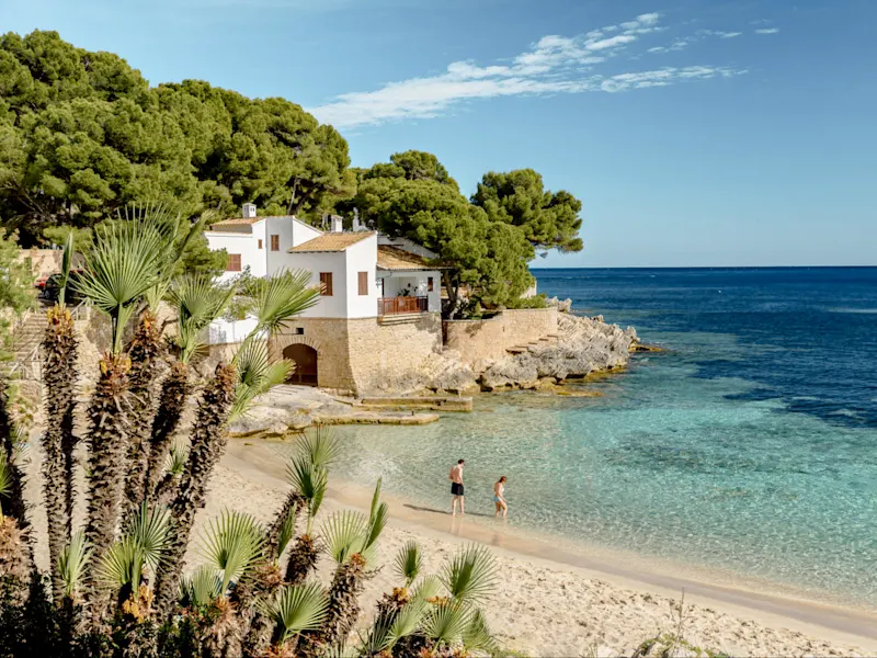 Spanien, Balearen, Mallorca Strand mit klarem Wasser und weißen Häusern. Mallorca, Balearen, Spanien.