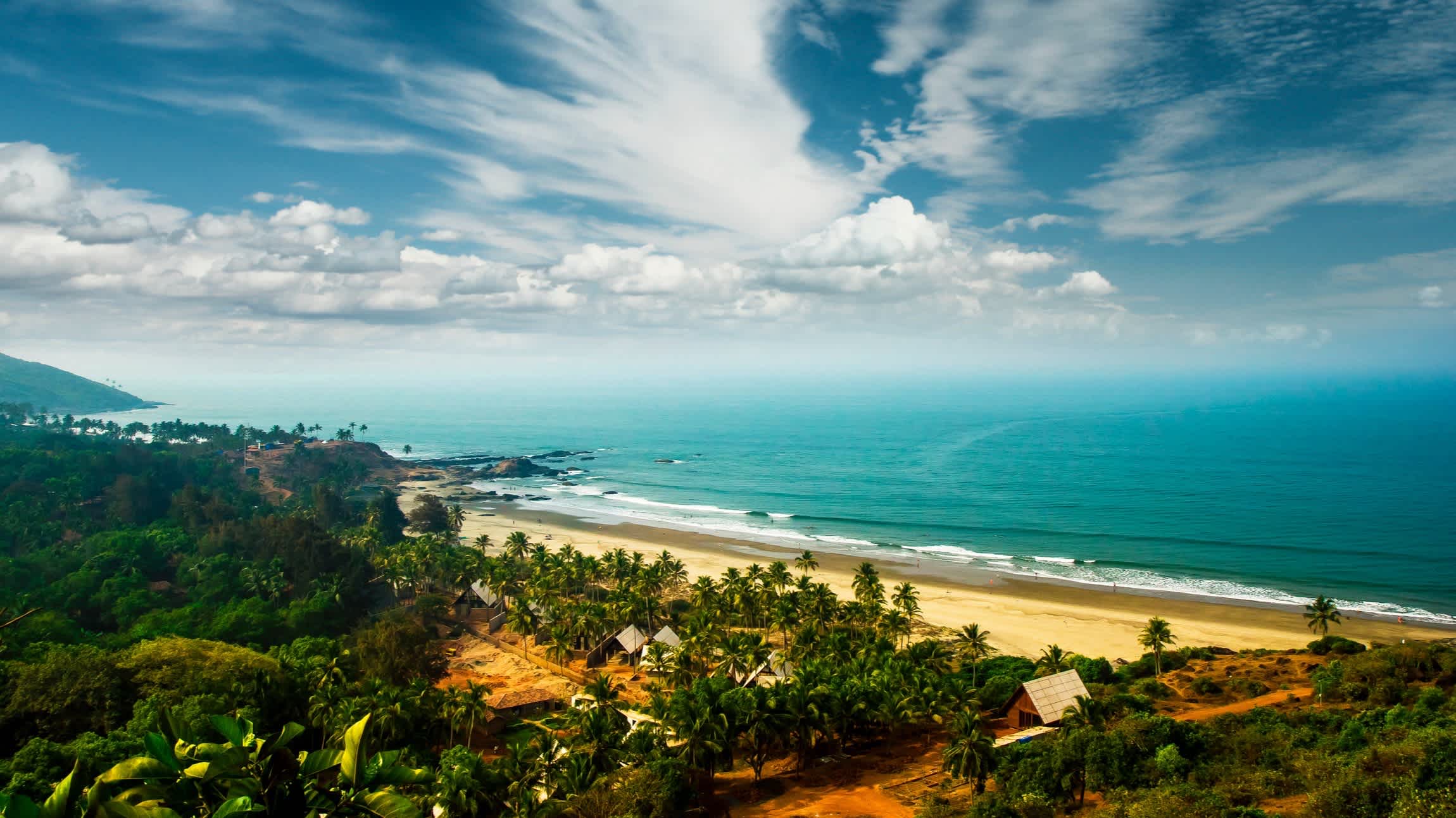 Luftaufnahme des Vagator Beach, Goa, Indien mit Palmen und dem Blauen Meer im Bild.
