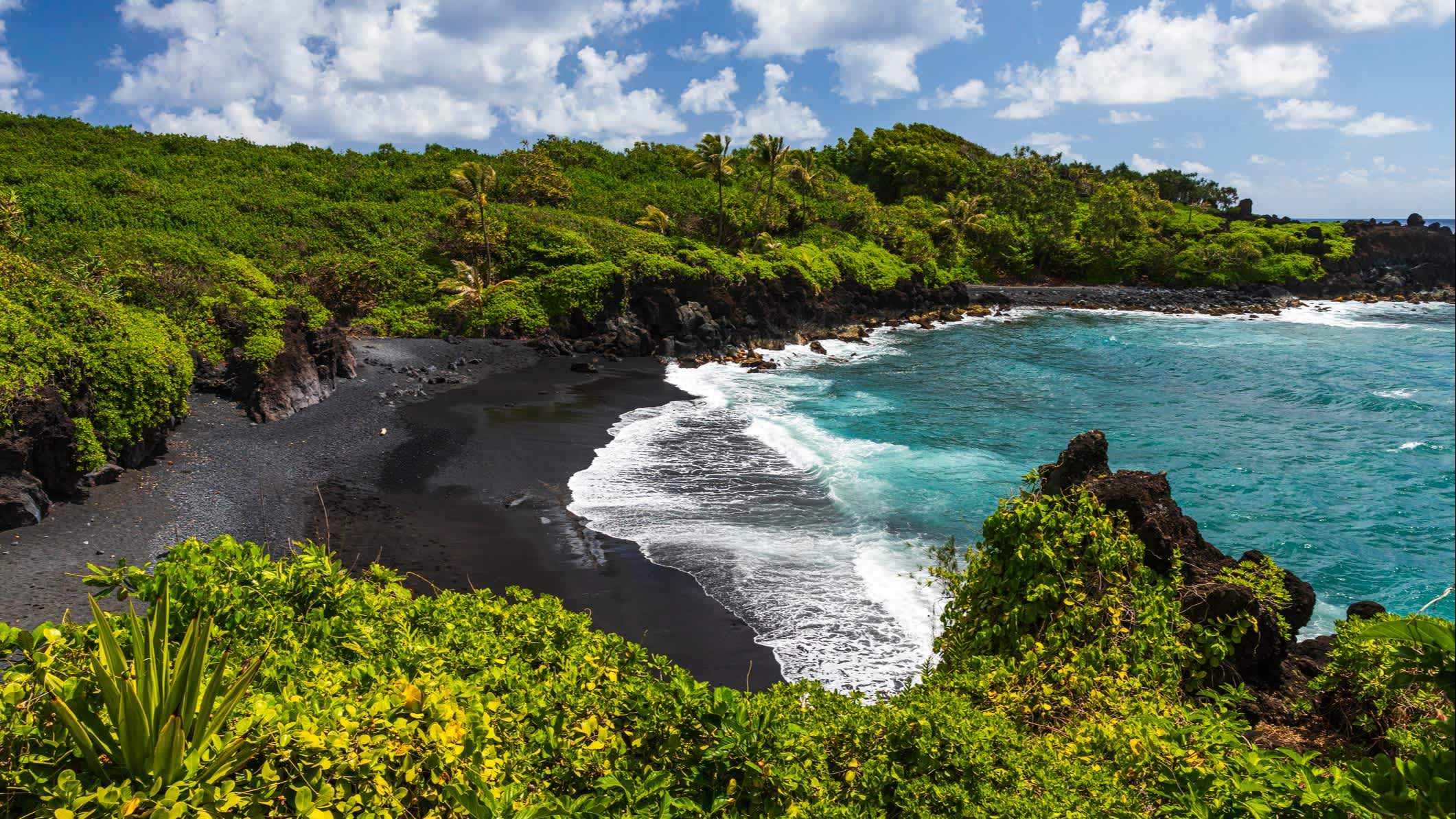 Schwarzer Sandstrand und Blick auf die Küste in Maui