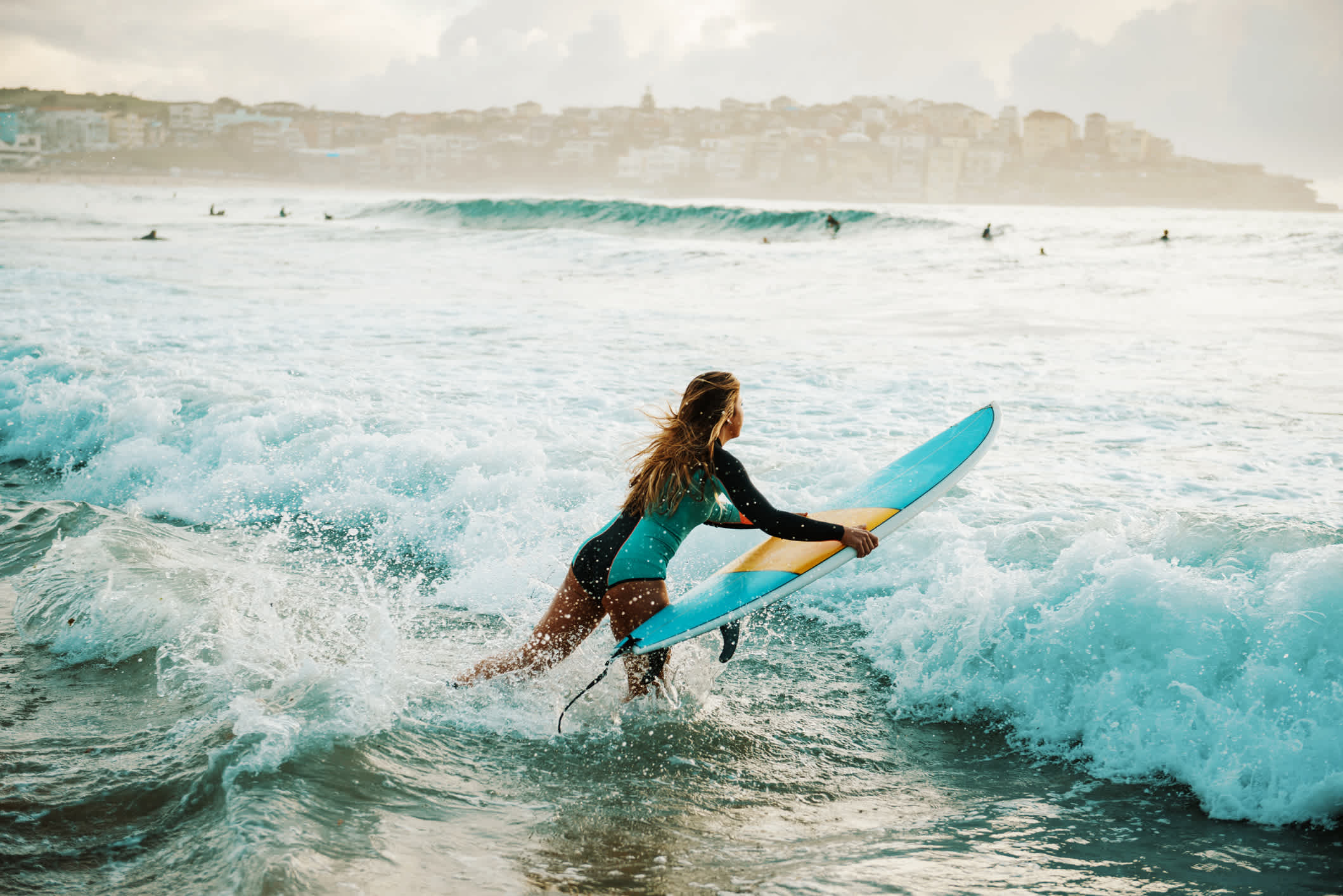 Eine Surferin, die sich am Strand Bondi Beach, Sydney, in die Wellen schmeißt.