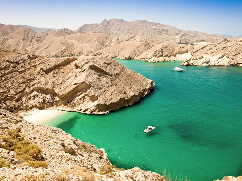 Eau turquoise et bateaux entre les rochers. Bandar Khairan, Mascate, Oman.