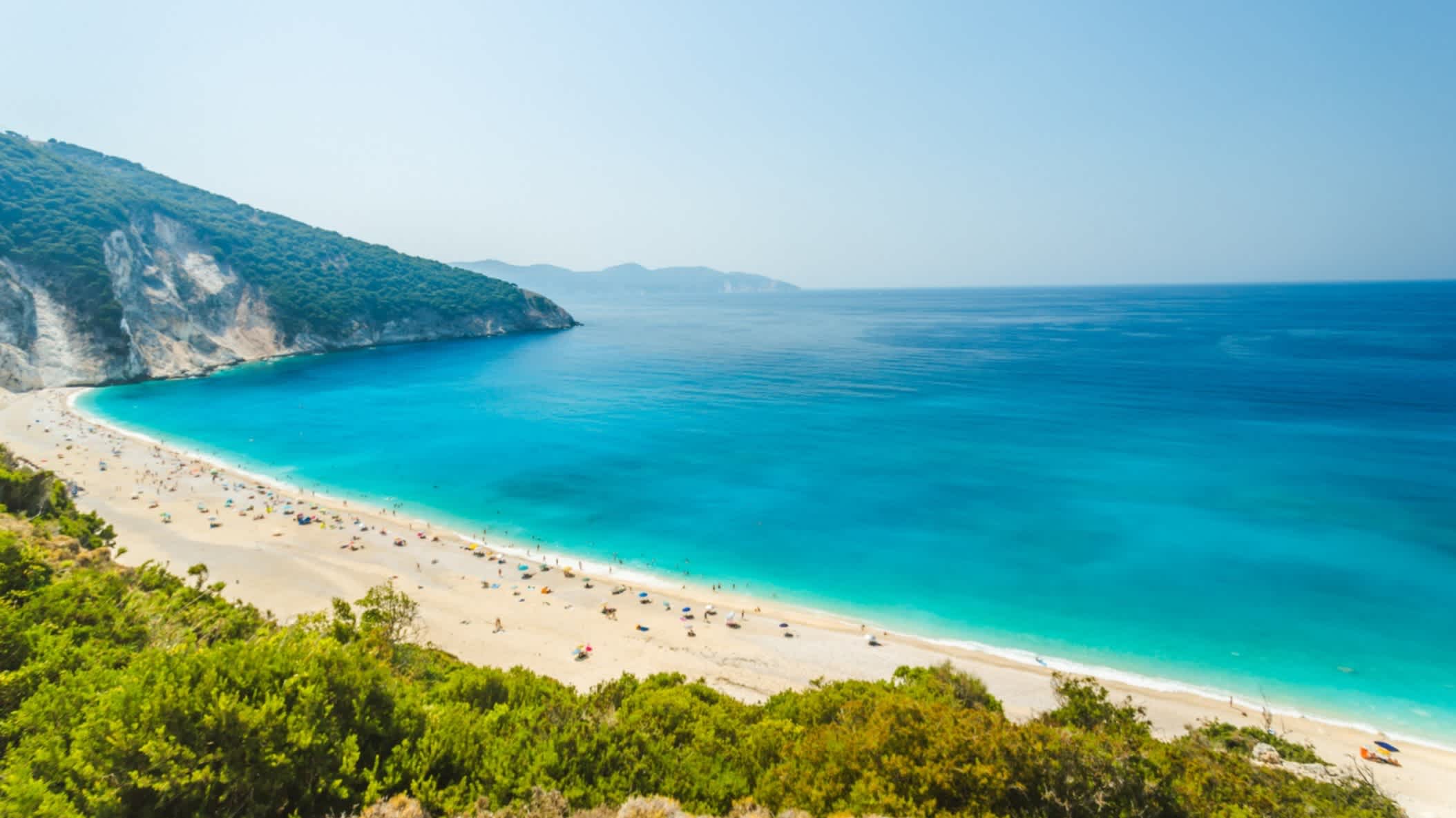 Schöner und berühmter Strand von Myrtos, Kefalonia, Griechenland mit dem weiten Meer, sowie dem Sandstrand und Bergen im Hintergrund.