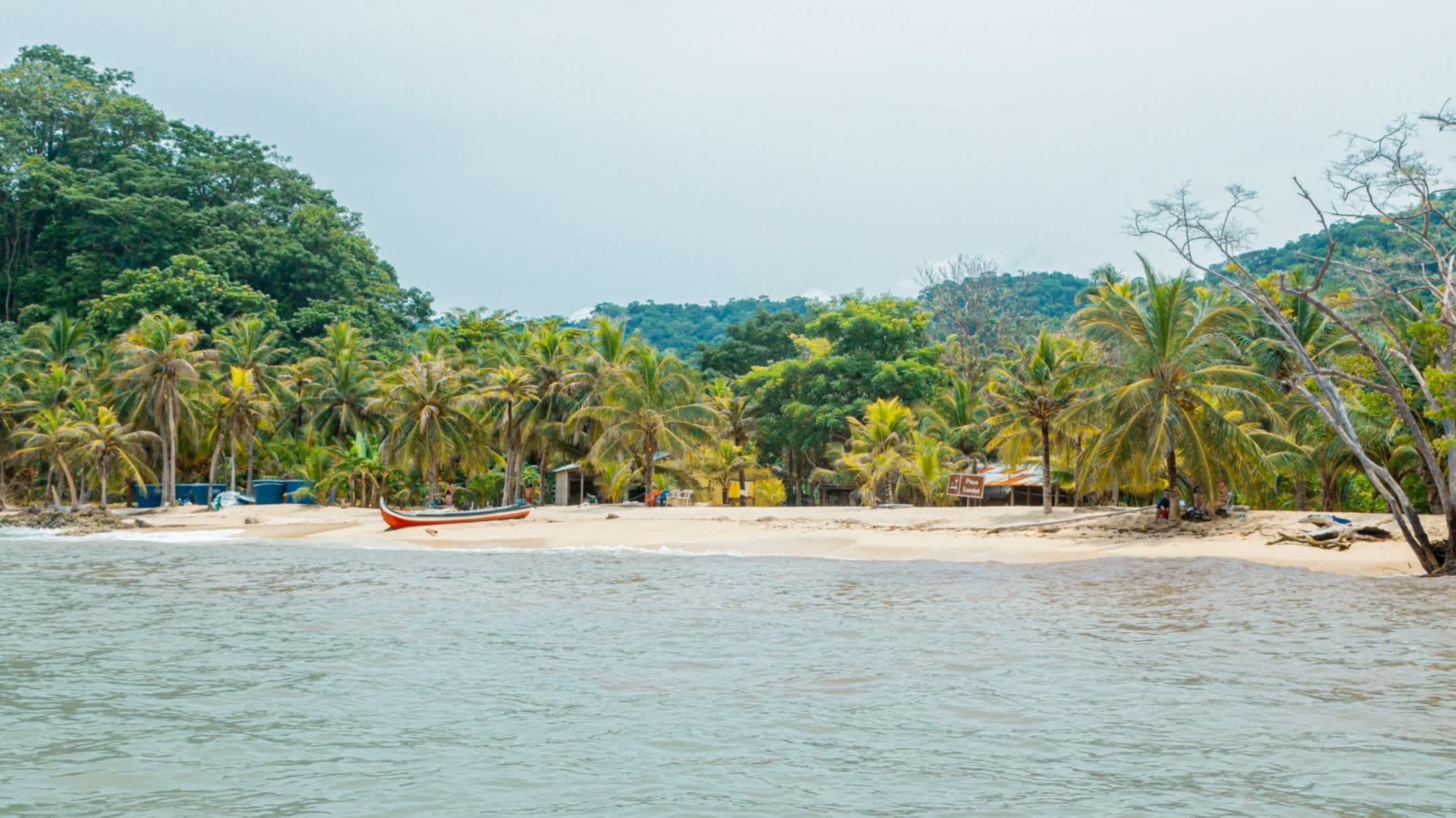 Der Strand von Capurgana Choco, Kolumbien, mit Blick vom Wasser aus auf den weißen Strand und Palmen. 