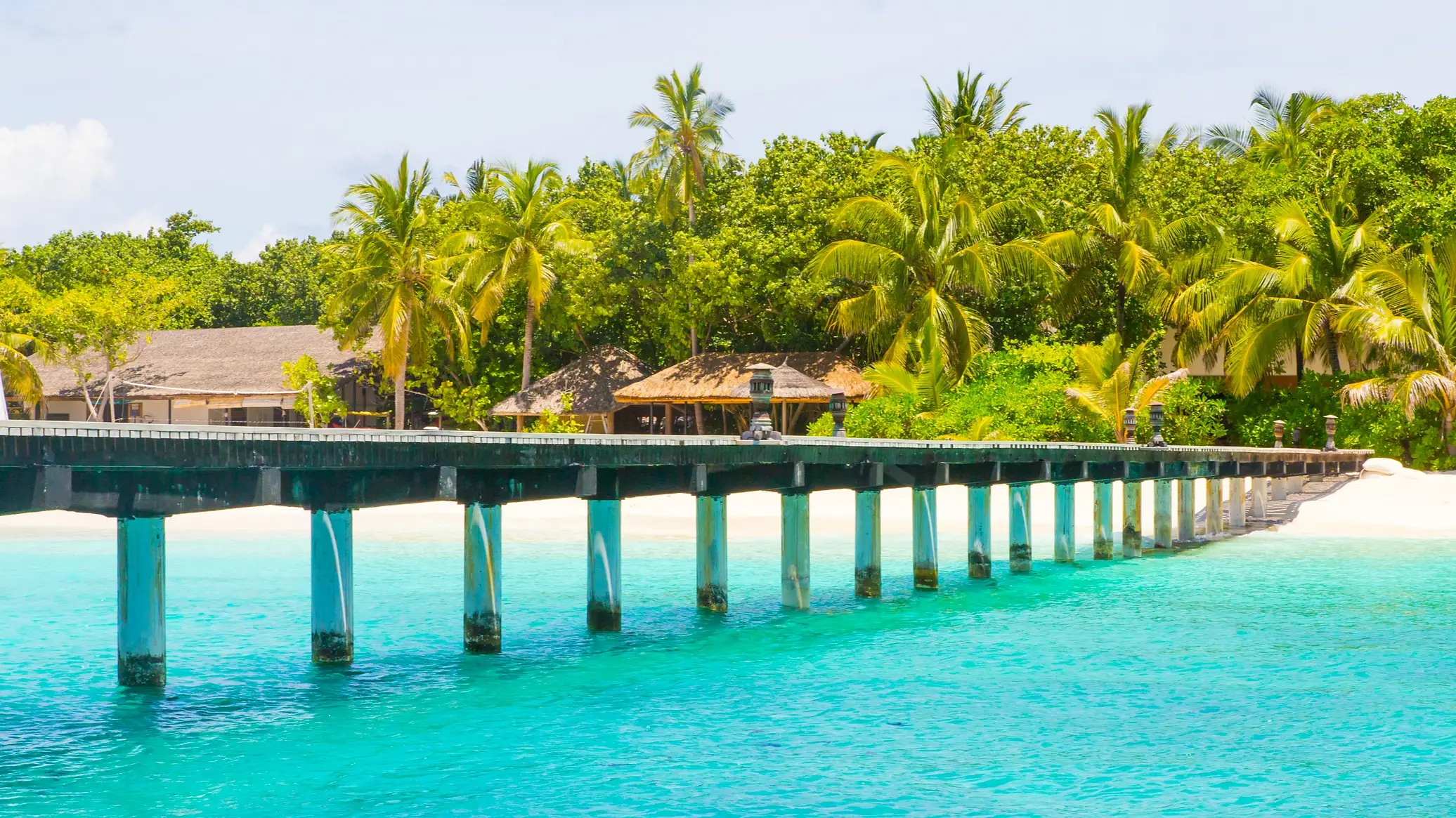 Malediven, Fonimagoodhoo Steg über dem türkisblauen Meer und Strand mit Palmen im Hintergrund