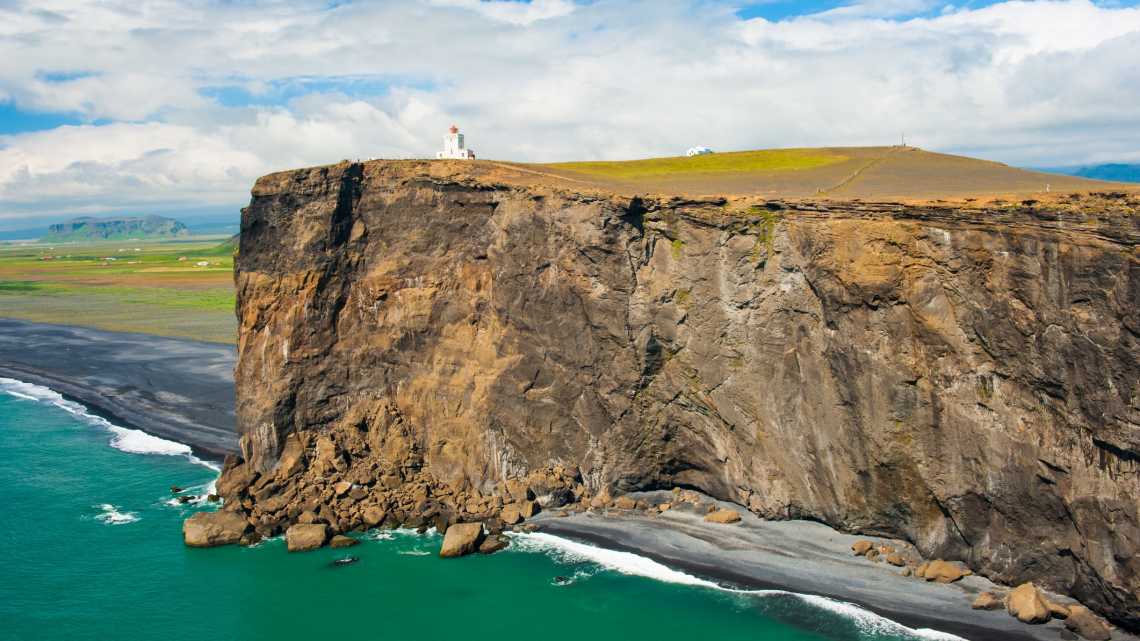 Un phare sur la falaise du cap Dyrholaey, Islande.

