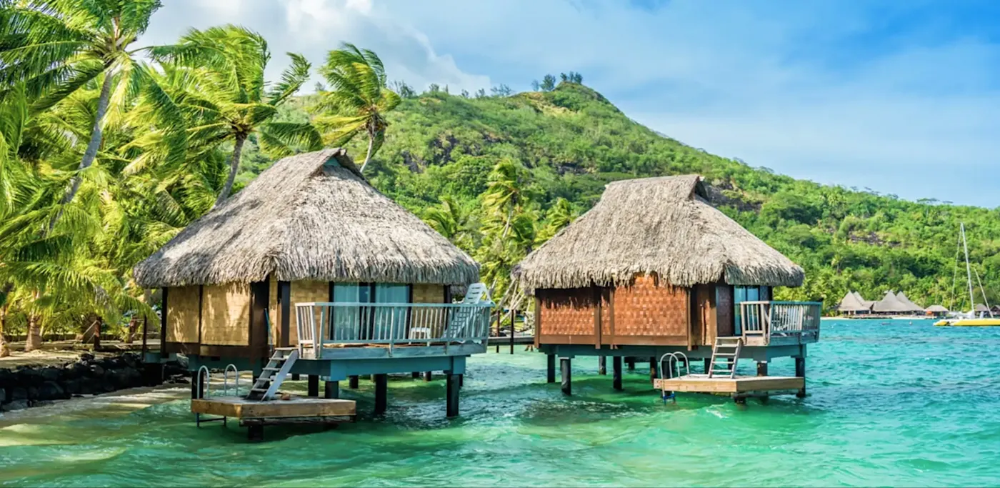 Bungalows sur l'eau avec palmiers, Vaitape, Bora Bora, Polynésie française.