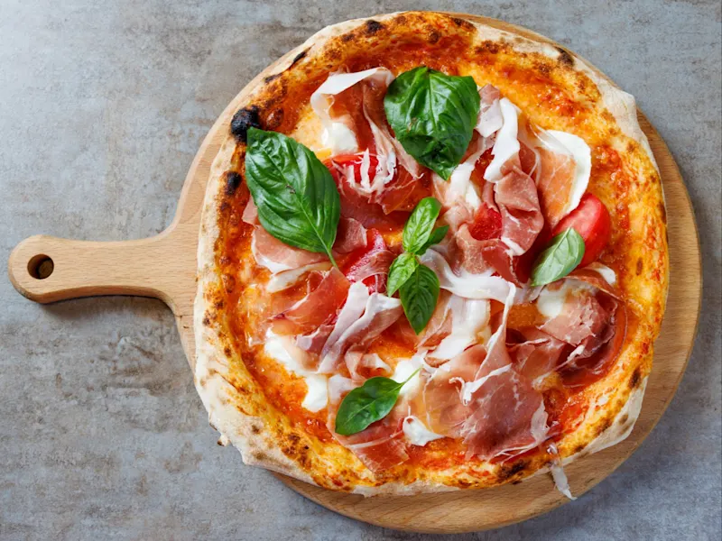 Pizza Prosciutto Crudo e Basilico, Italien Pizza mit Prosciutto Crudo und frischem Basilikum kombiniert den salzigen Geschmack des Schinkens mit der Frische der Kräuter