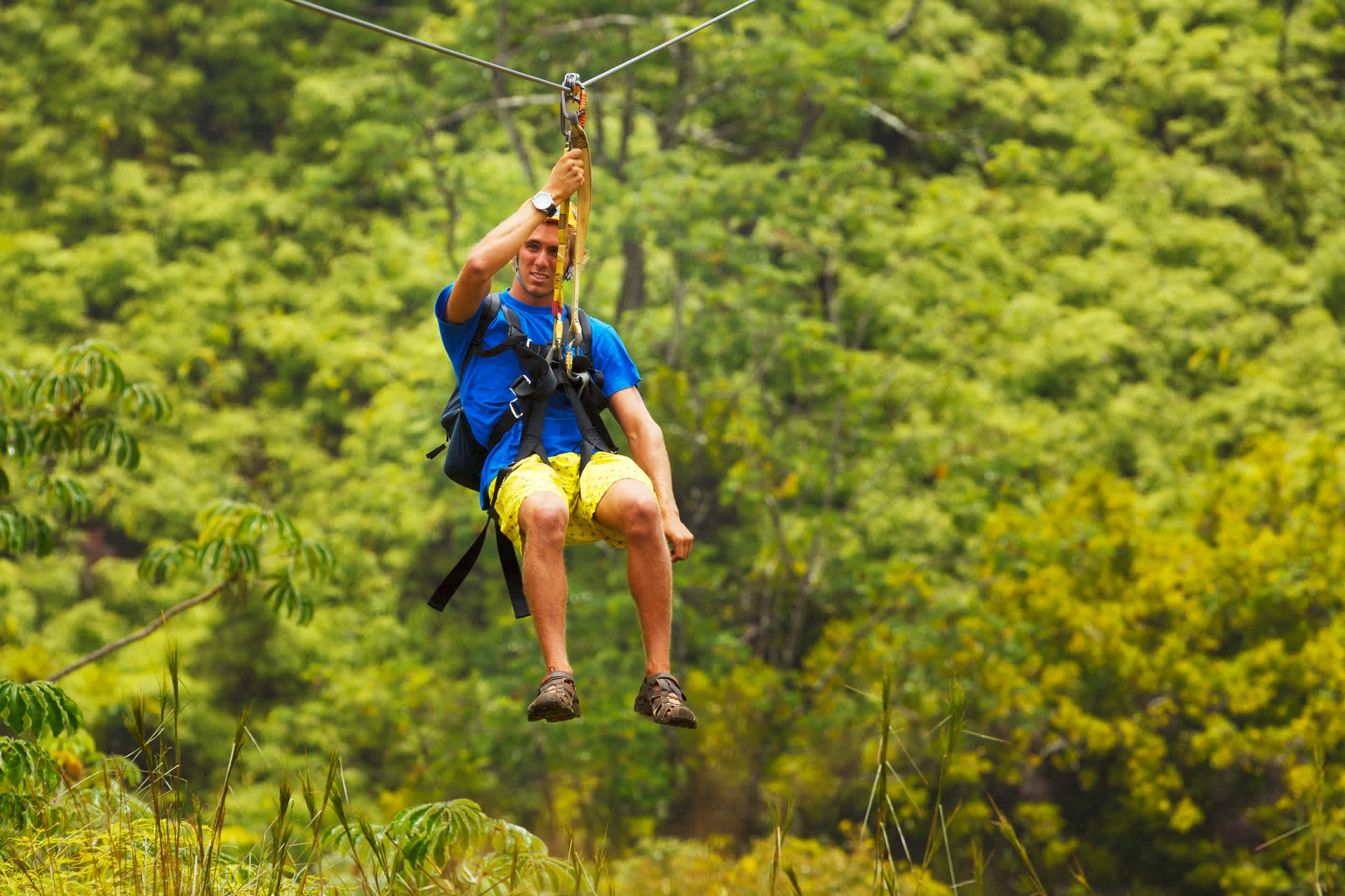 Mann auf einem Zipline über einem üppigen tropischen Tal