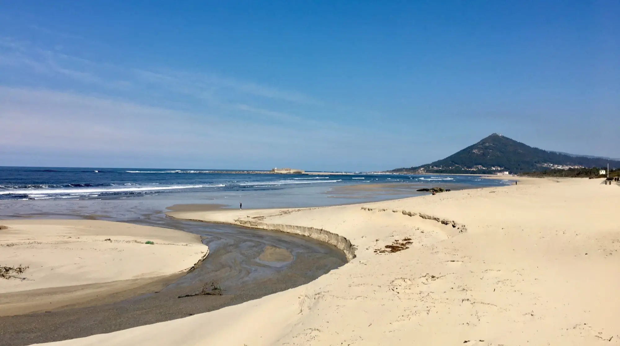 Vue sur le sable blanc et l'eau de la plage de Moledo avec les montagnes en arrière-plan, au Portugal. 