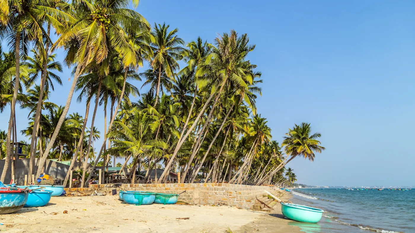 Plage avec palmiers et bateaux typiques, Mui Né, Vietnam