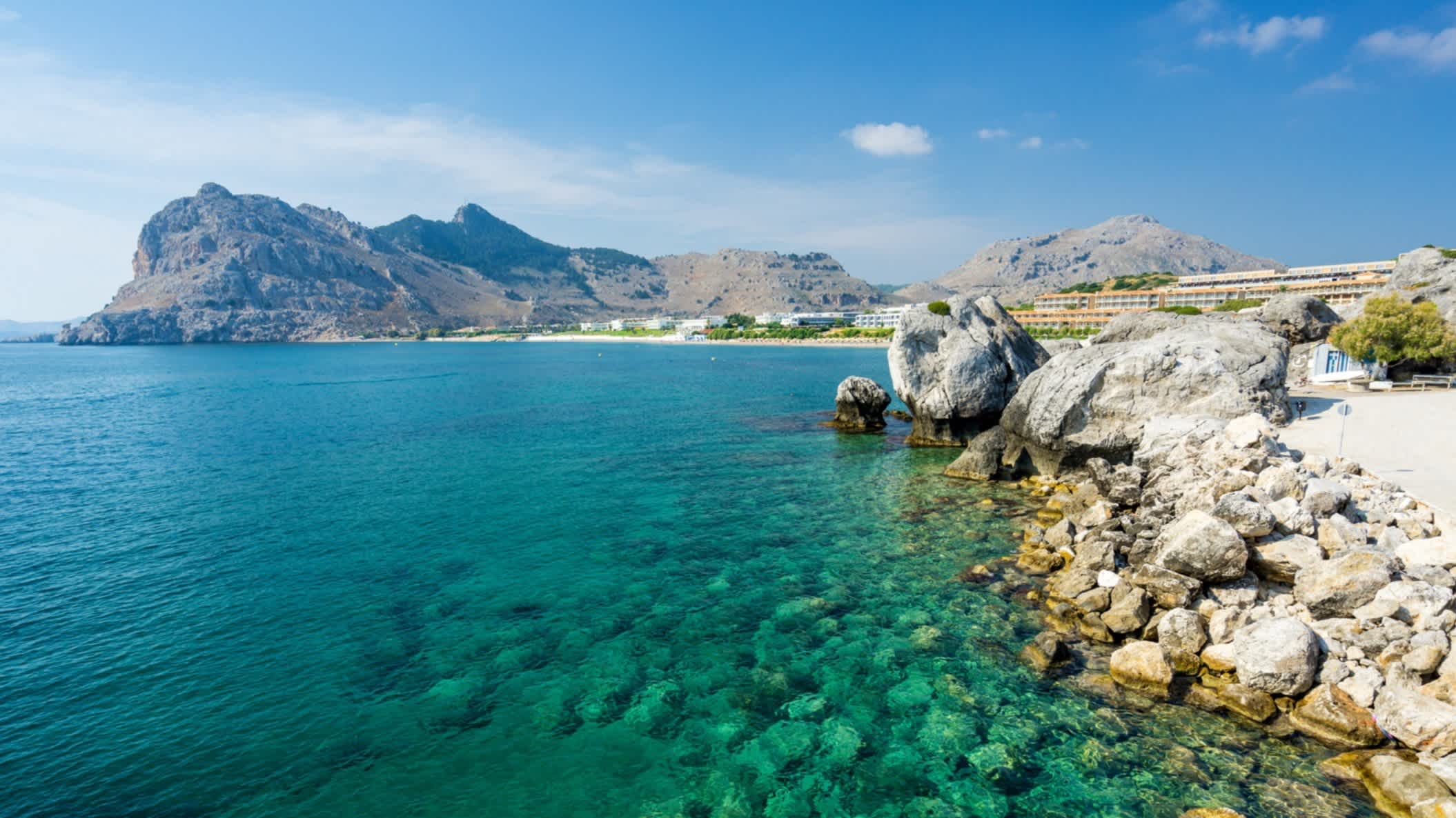 Die Küstenlandschaft bei Kolymbia auf der griechischen Insel Rhodos, Griechenland bei Sonnenschein, blauem Himmel und mit Felsküsten im Hintergrund.

