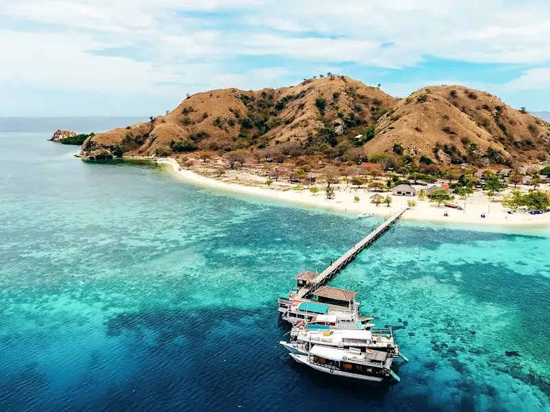 Indonesien, Ost-Nusa Tenggara, Flores Insel Türkisfarbenes Wasser und sandige Küste mit grünen Hügeln. Flores, Ost-Nusa Tenggara, Indonesien.