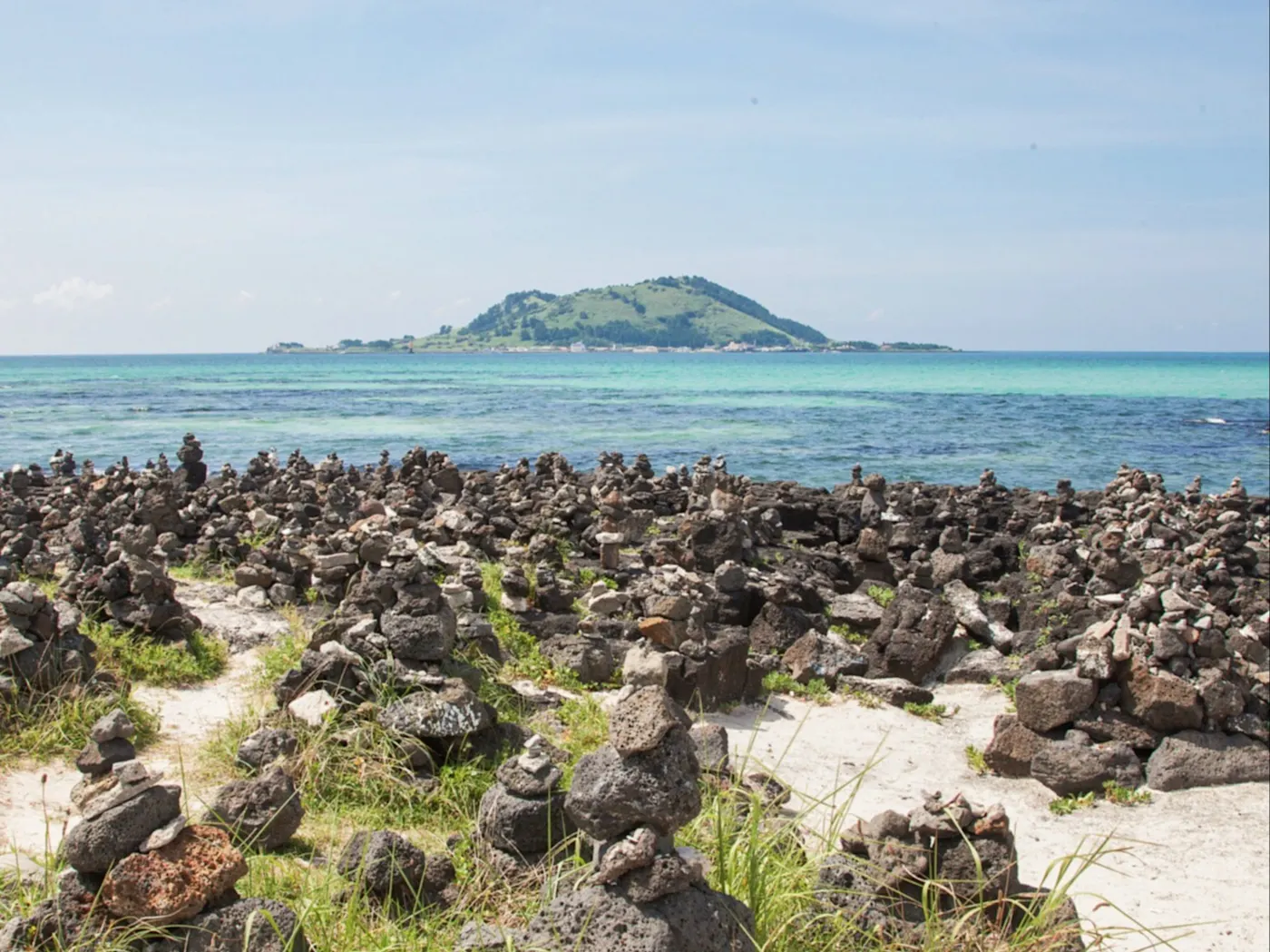 Der Strand von Jeju Island in Südkorea bietet eine spektakuläre Aussicht auf die Insel, mit aufeinander gestapelten Steinen, die am Ufer entlang liegen und eine friedliche, naturverbundene Atmosphäre schaffen