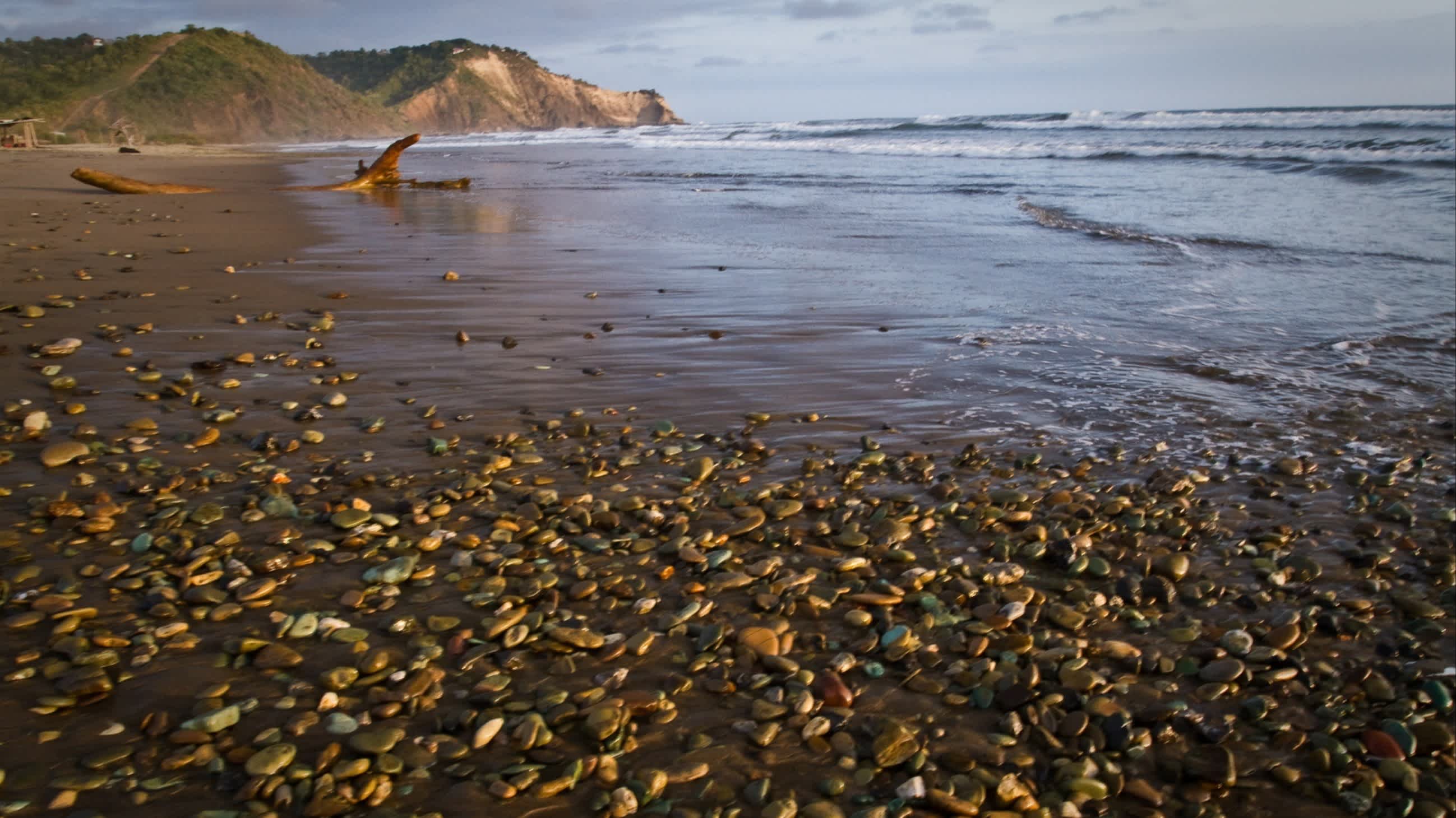 Der Strand von Ayampe, Provinz Manabí, Ecuador bei bewölktem Wetter und mit dem dunklen Strand und Kieselsteinen im Bild.