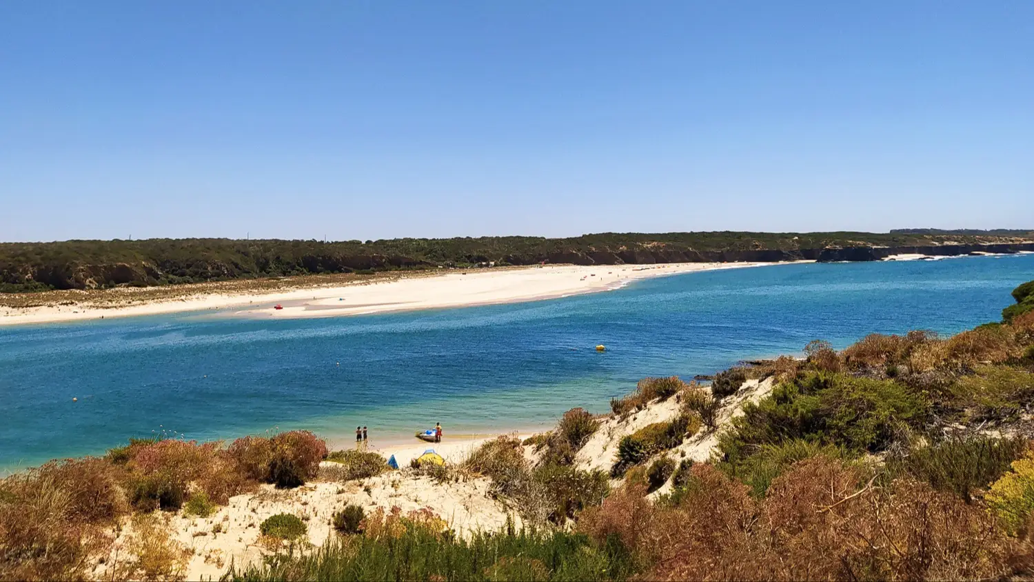 Der Naturstrand Praia da Franquia, Alentejo, Portugal, mit Blick durch die Dünen auf das Wasser und bei Sonnenschein.
