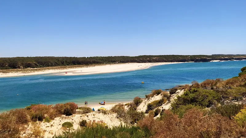 Der Naturstrand Praia da Franquia, Alentejo, Portugal, mit Blick durch die Dünen auf das Wasser und bei Sonnenschein.