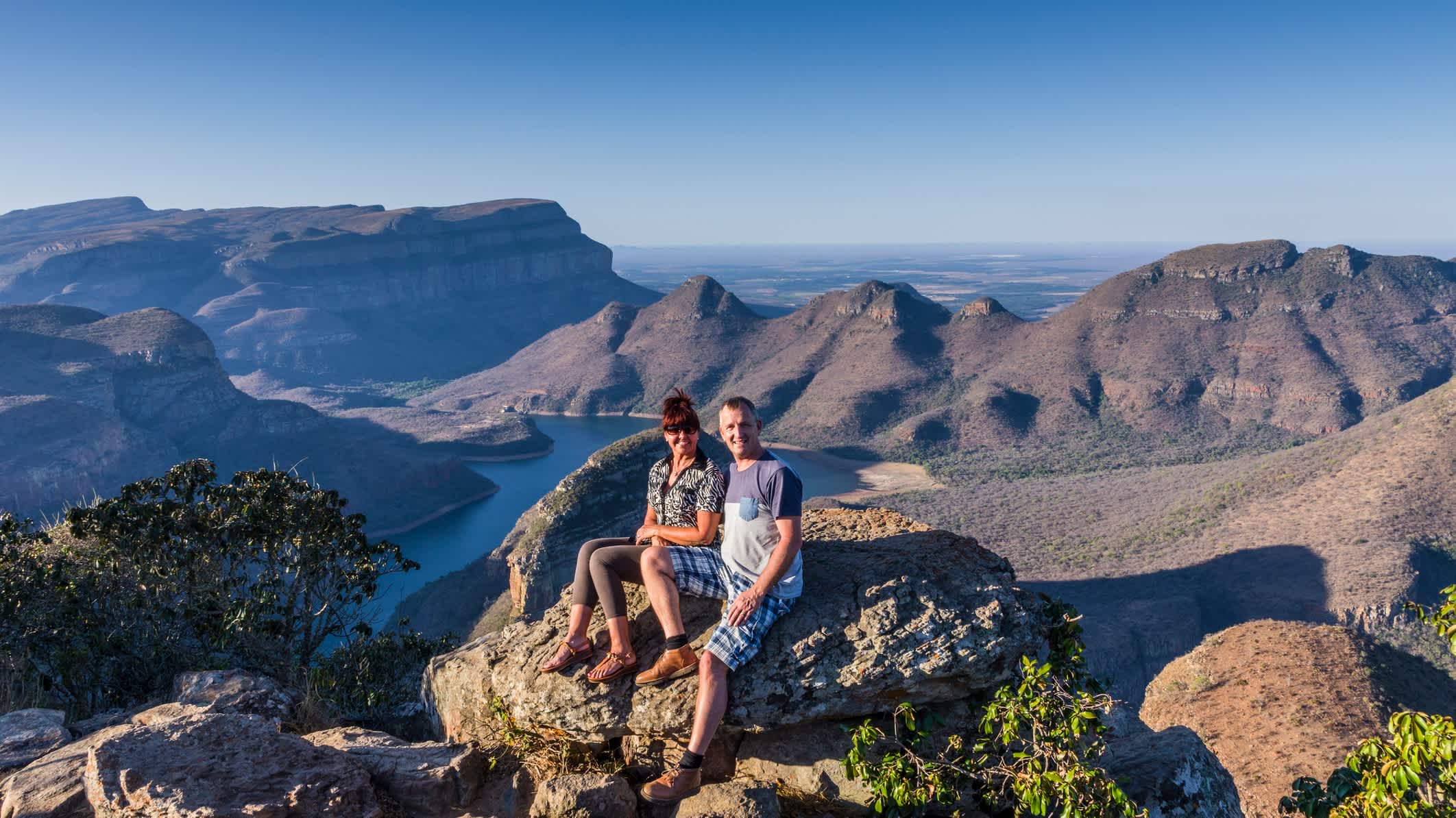 Ein Mann und eine Frauen sitzen hoch über dem Blyde River Canyon in Südafrika