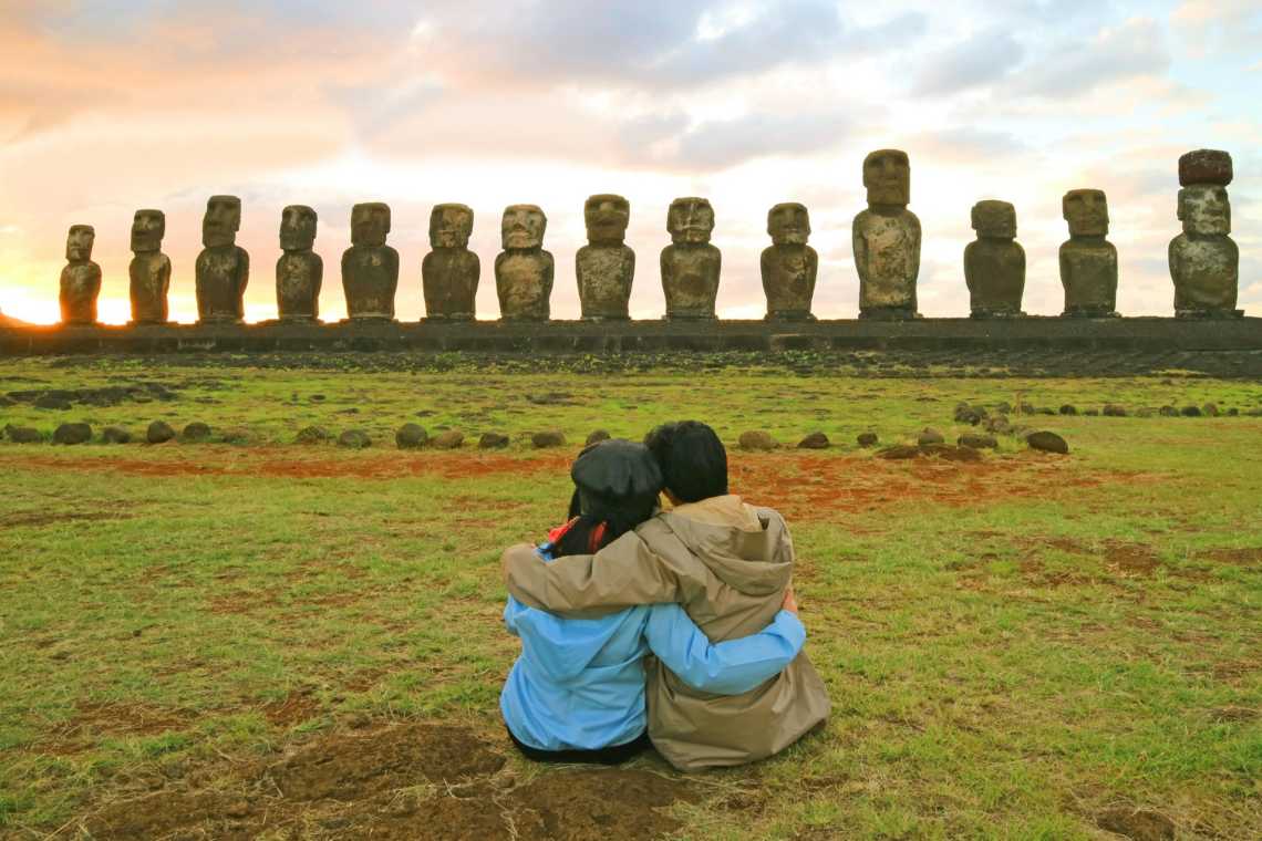 Un couple devant les statues de l'île de Pâques pendant un voyage de noces au Chili.