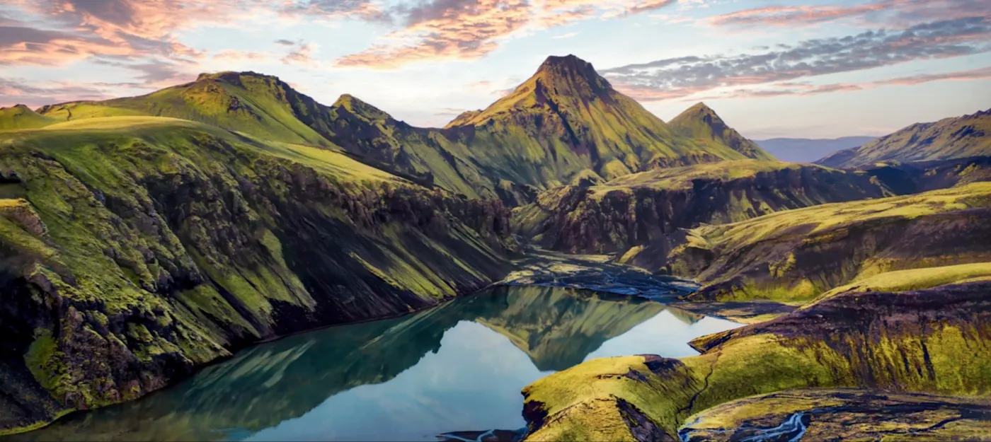 Montagnes vertes et lac calme sous un ciel dramatique. Uxatindar, Hautes Terres, Islande.