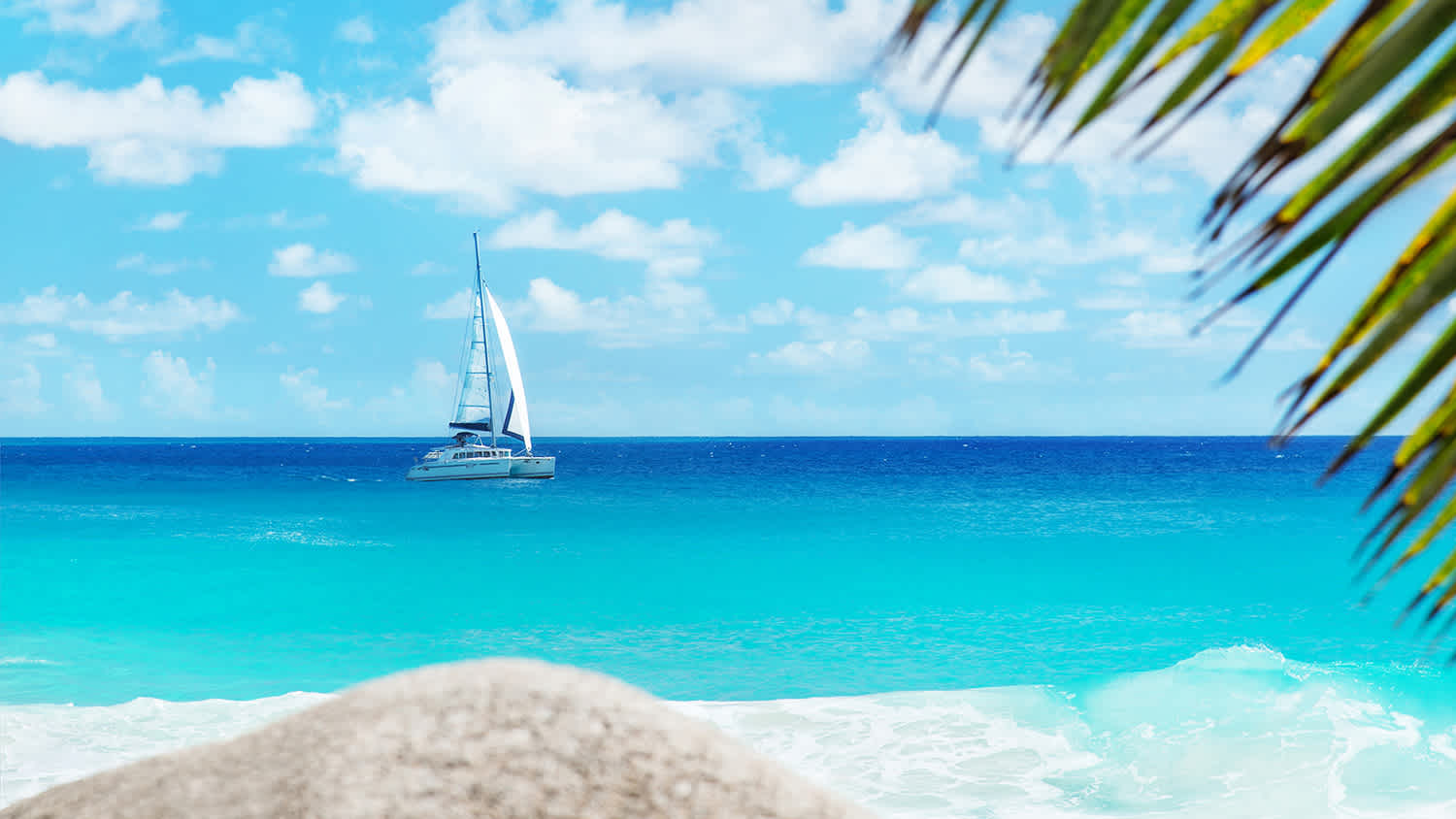 Segelboot im türkisfarbenen Wasser am Strand der Seychellen