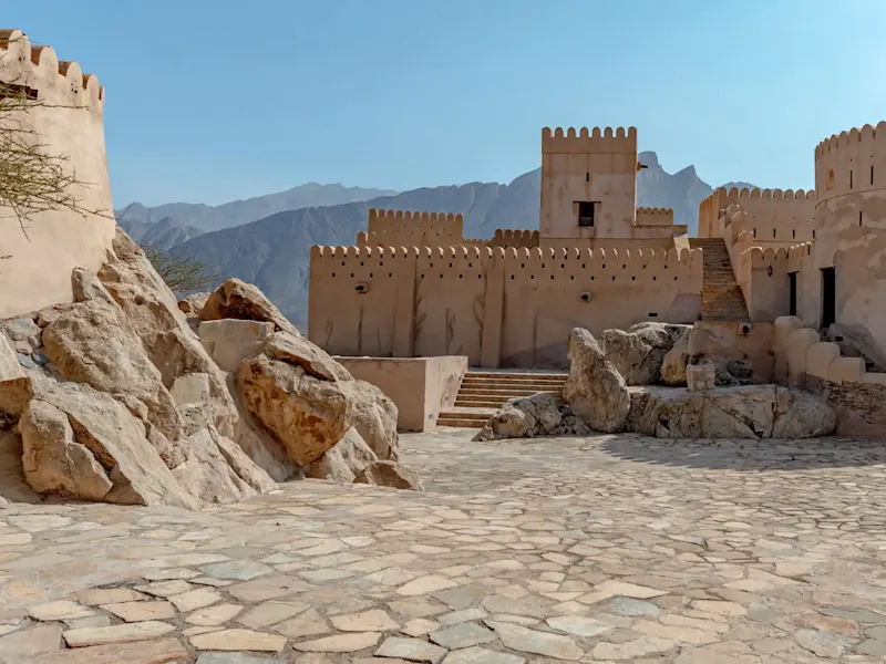 Ancienne forteresse en pierre avec un panorama de montagnes en arrière-plan. Nizwa, Oman.