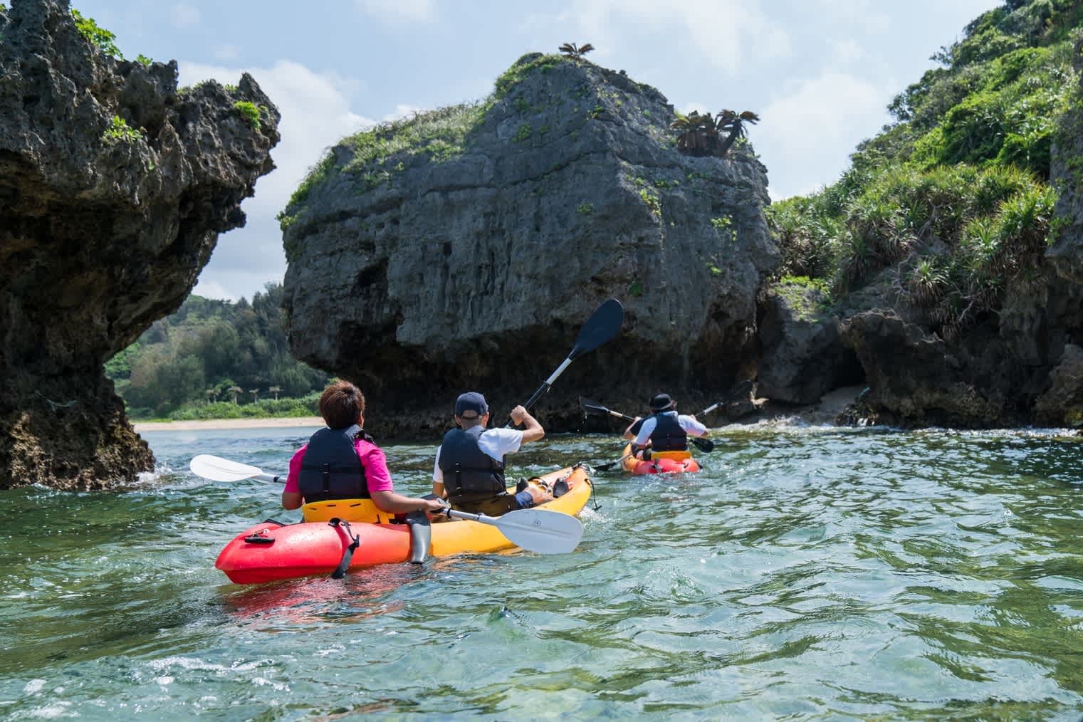 Eine Reisegruppe bei einer Kajaktour auf dem Wasser umgeben von großen Felsen