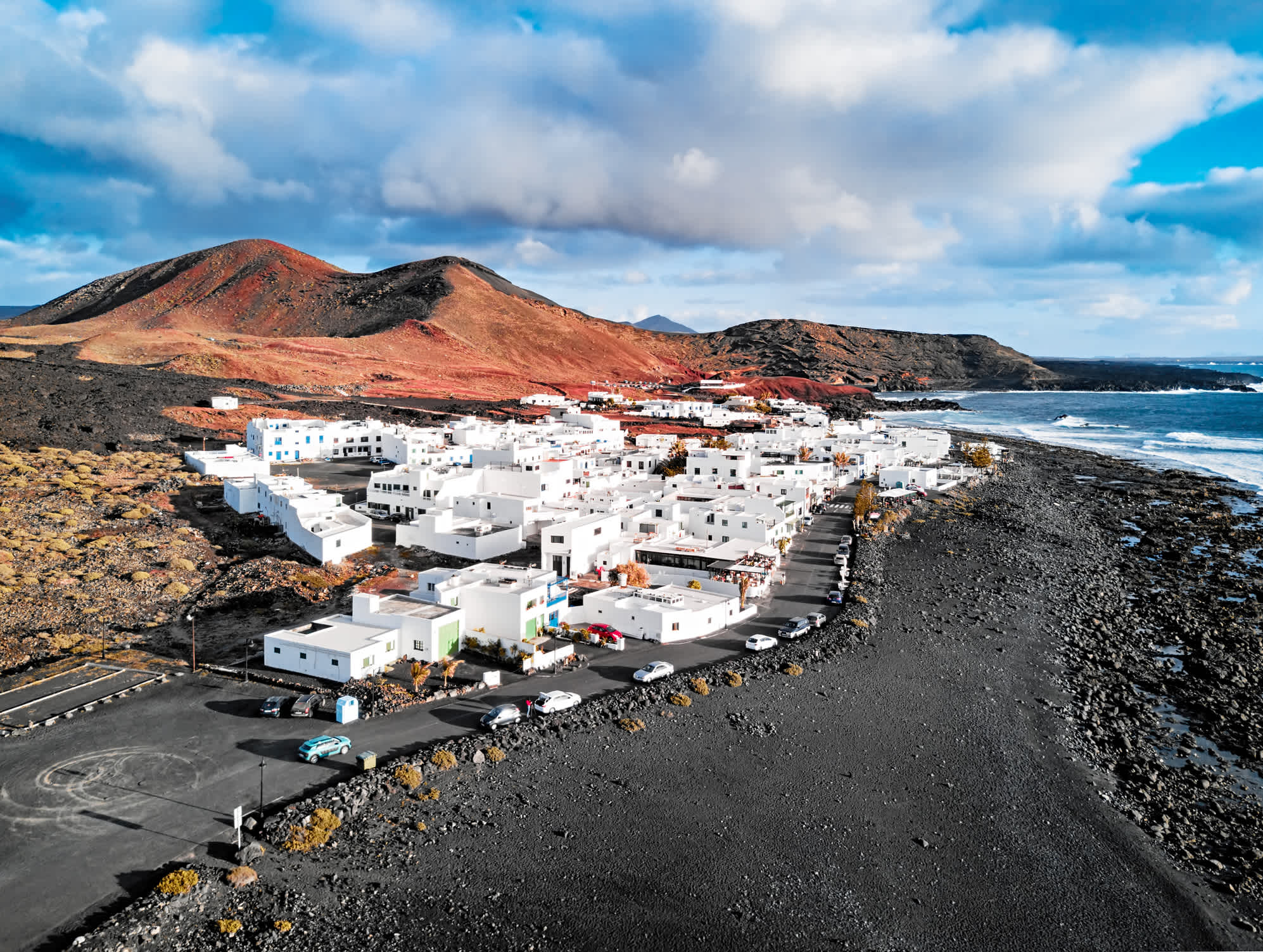 Kleines Dorf mit weißen Häusern an der Küste Lanzarotes auf schwarzen Gestein 