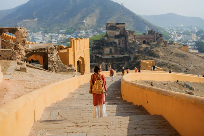 Frau, die auf einer Treppe vor dem Hintergrund der Festung Amber geht.


