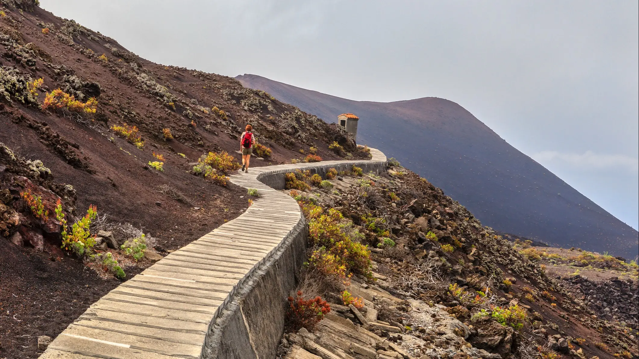 Frau auf der Vulkanroute, einem Weg, der vulkanische Landschaften von außergewöhnlicher Schönheit durchquert, wo Sie die verschiedenen Merkmale der Insel La Palma bewundern können. Dieses Foto wurde rund um den Vulkan Teneguía aufgenommen, dessen letzter Ausbruch auf das Jahr 1971 zurückgeht, der letzte auf der Insel. La Palma, Kanarische Inseln, Spanien.



