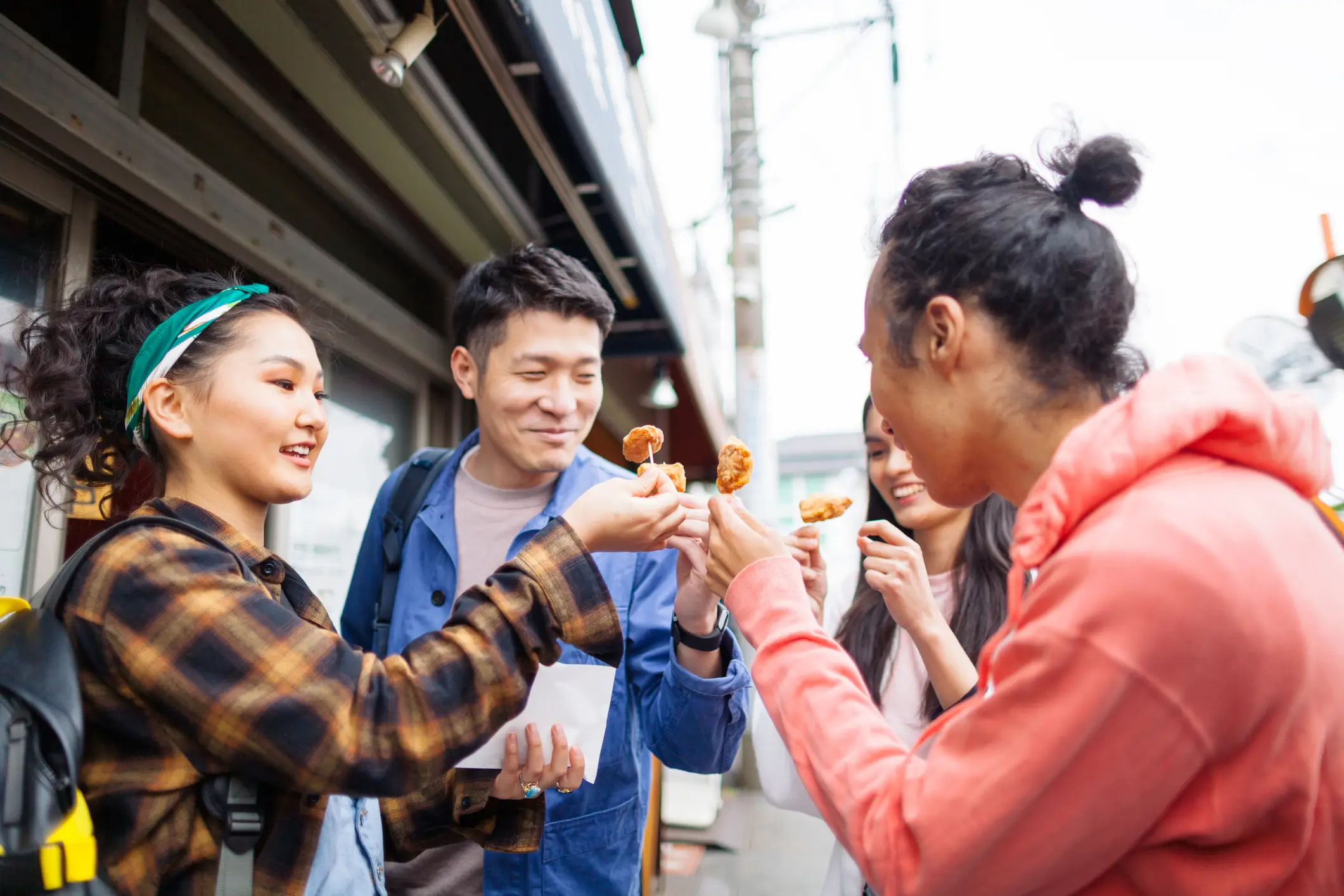 Japan, Streetfood-Tour Gruppe aus Freunden und einem Guide, die japanisches Streetfood probiert