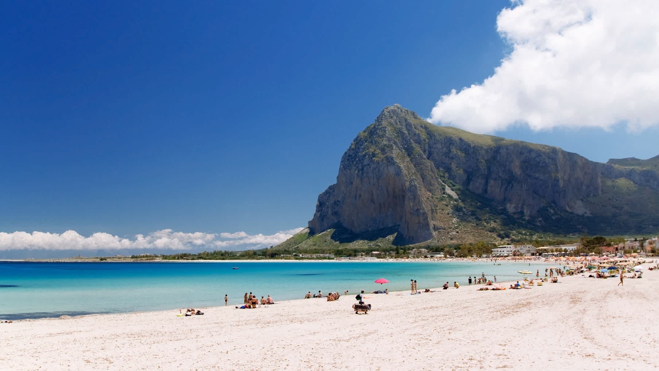 Blick zum Strand in San Vito Lo Capo, Sizilien, Italien mit einem imposanten Berg, blauem Wasser und weißem Sand.