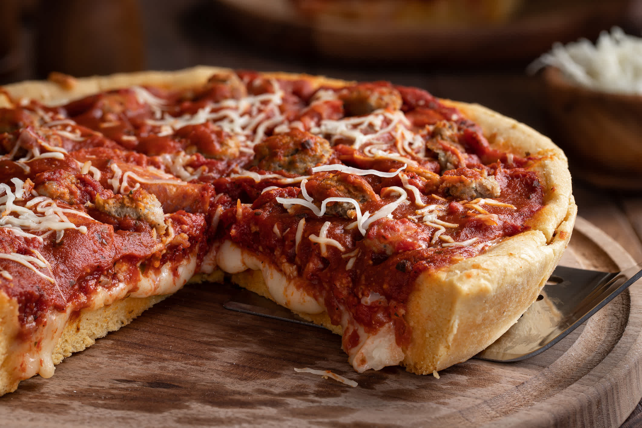 Nahaufnahme einer Pizza nach Chicagoer Art auf einer Holzplatte.

