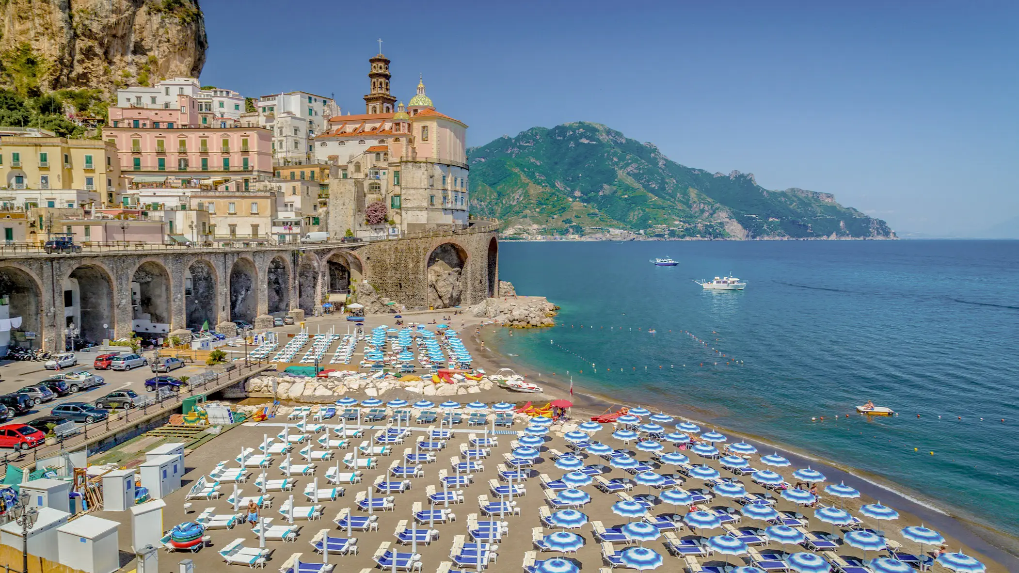 View of the sandy beach of Atrani with colorful umbrellas and the old town in the background