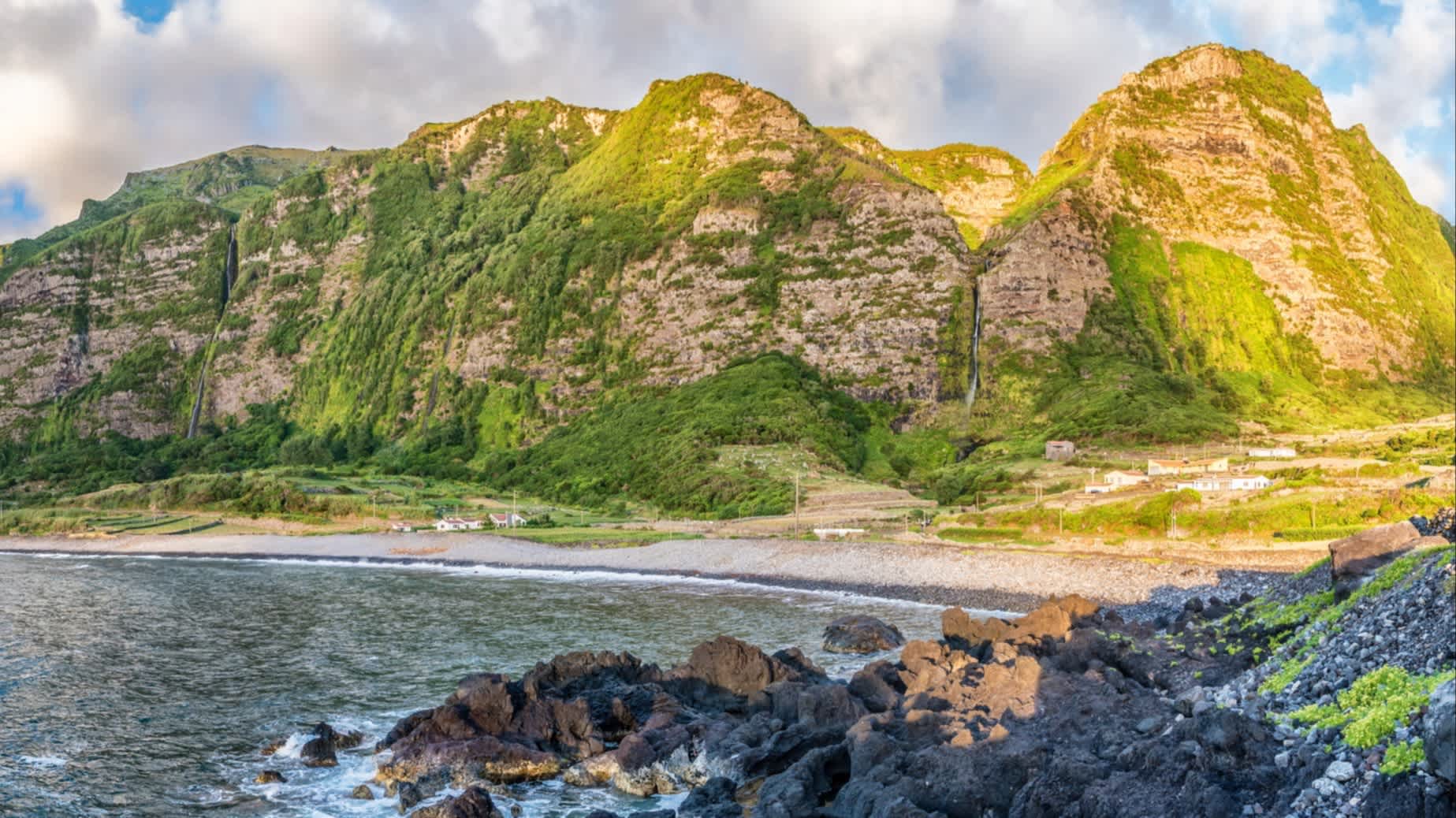 Blick auf den Fajã Grande auf der Insel Flores, Azoren, Portugal mit einem imposantem Gebirge im Hintergrund.