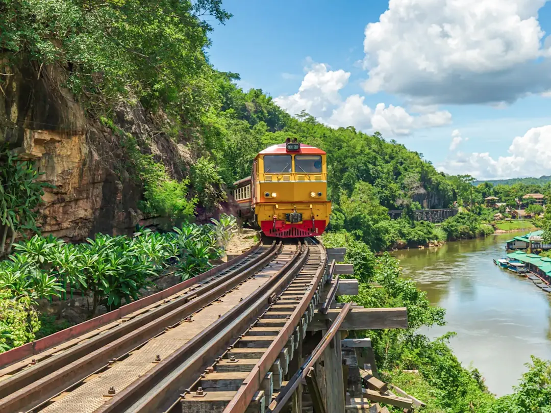 Gelber Zug fährt durch den dichten Dschungel entlang der Death Railway, Kanchanaburi, Thailand.
