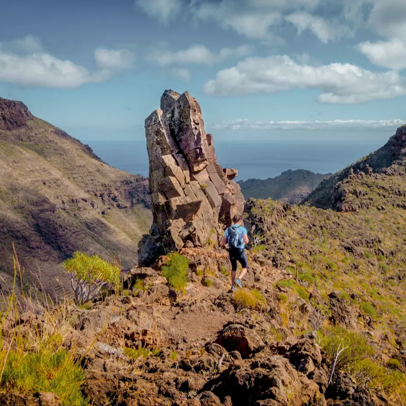 Wanderer in felsiger Landschaft mit Blick aufs Meer. Agaete, Gran Canaria, Spanien.