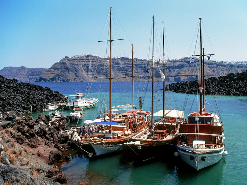 Griechenland, Santorini, Nea Kameni Segelboote am Hafen mit Vulkanhintergrund. Nea Kameni, Santorini, Griechenland.