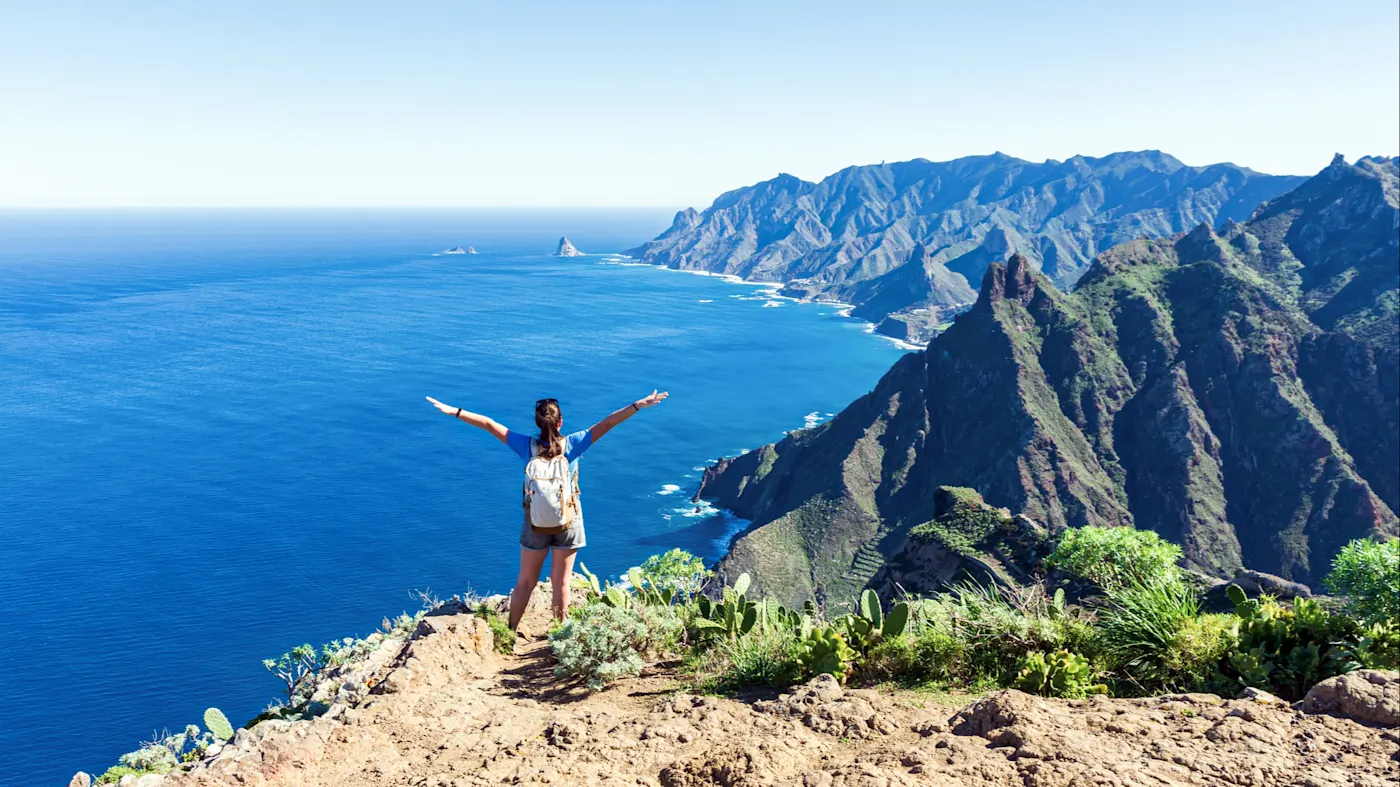 Spanien, Teneriffa, Anaga Frau auf Klippe mit Blick aufs Meer und Berge. Anaga, Teneriffa, Spanien.