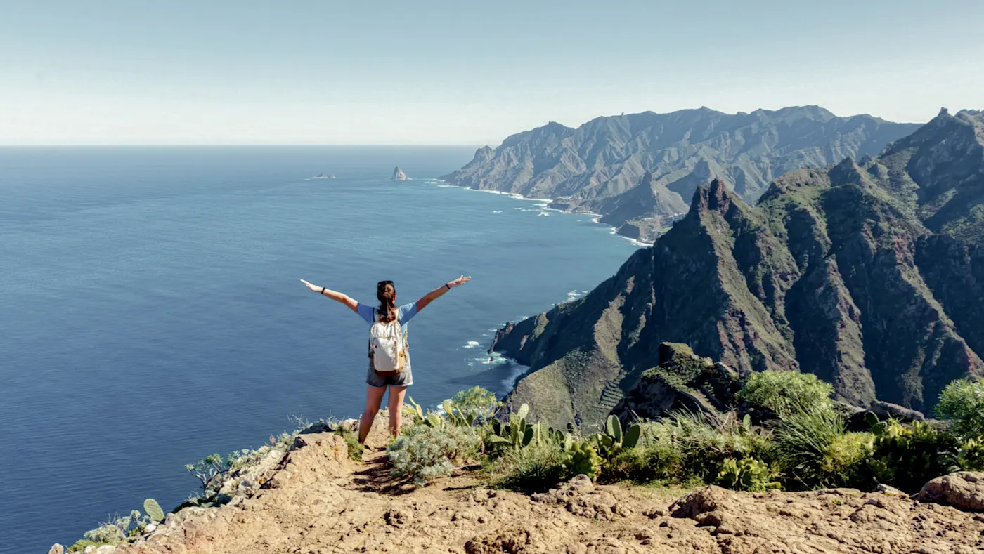 Frau auf Klippe mit Blick aufs Meer und Berge. Anaga, Teneriffa, Spanien.
