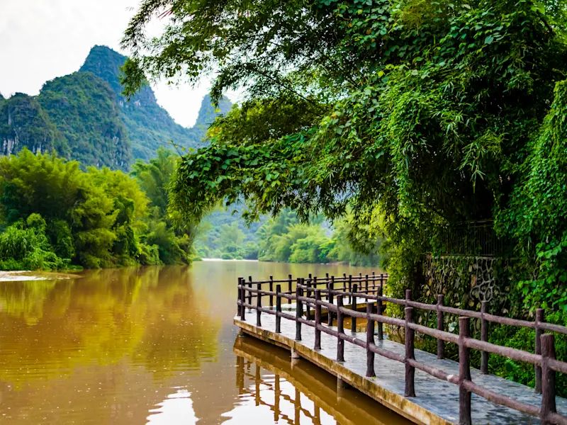 Atemberaubende Landschaft von Yangshuo mit Karstbergen und Holzbrücke, die entlang des Ufers des Li-Flusses verläuft, Guangxi, China.


