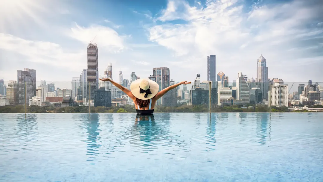 Frau im Infinity-Pool mit Blick auf die Skyline. Bangkok, Zentralregion, Thailand.