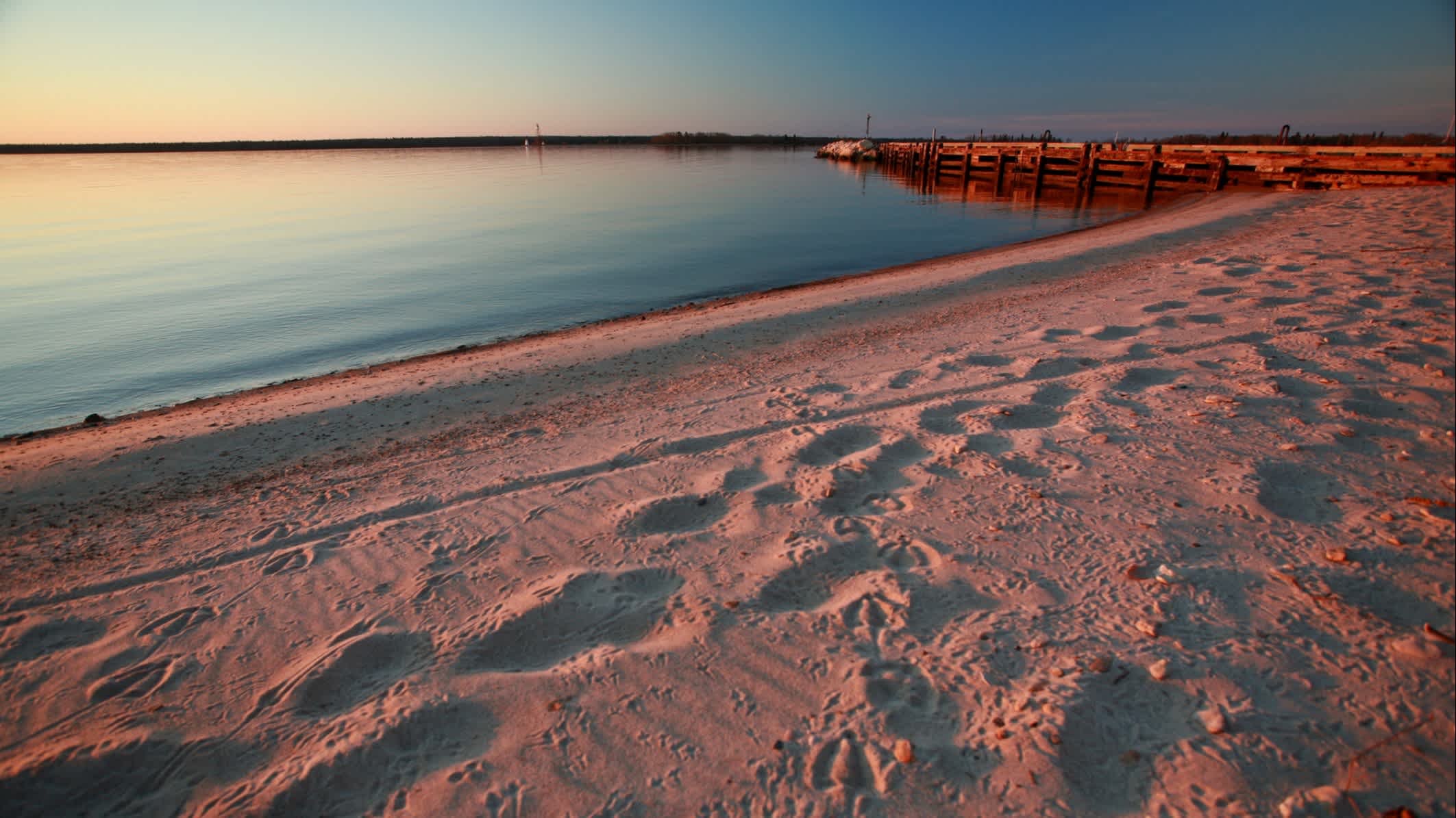 Sandstrand am Lake Winnipeg in Kanada bei rötlicher Sonnendämmerung.