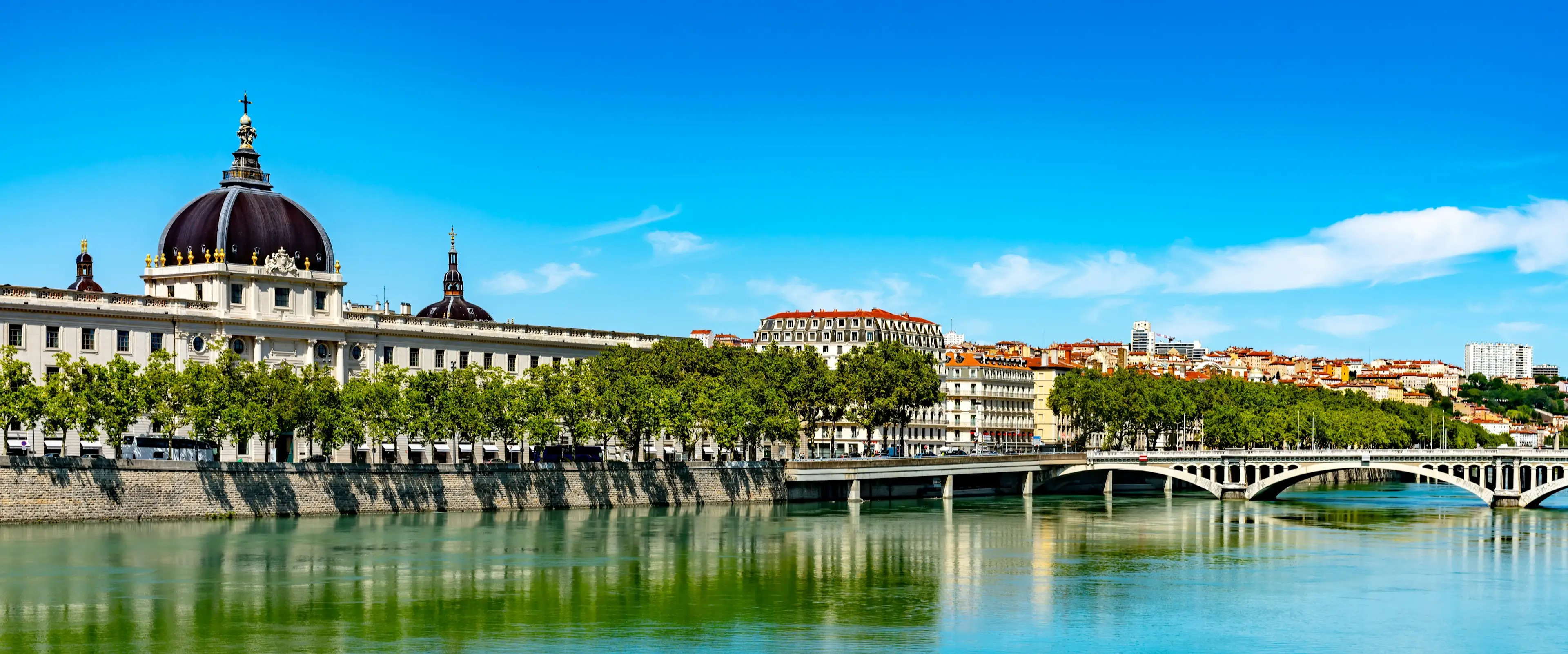 Vue panoramique de Lyon avec le dôme de l'Hôtel-Dieu, la rivière Rhône et un pont.