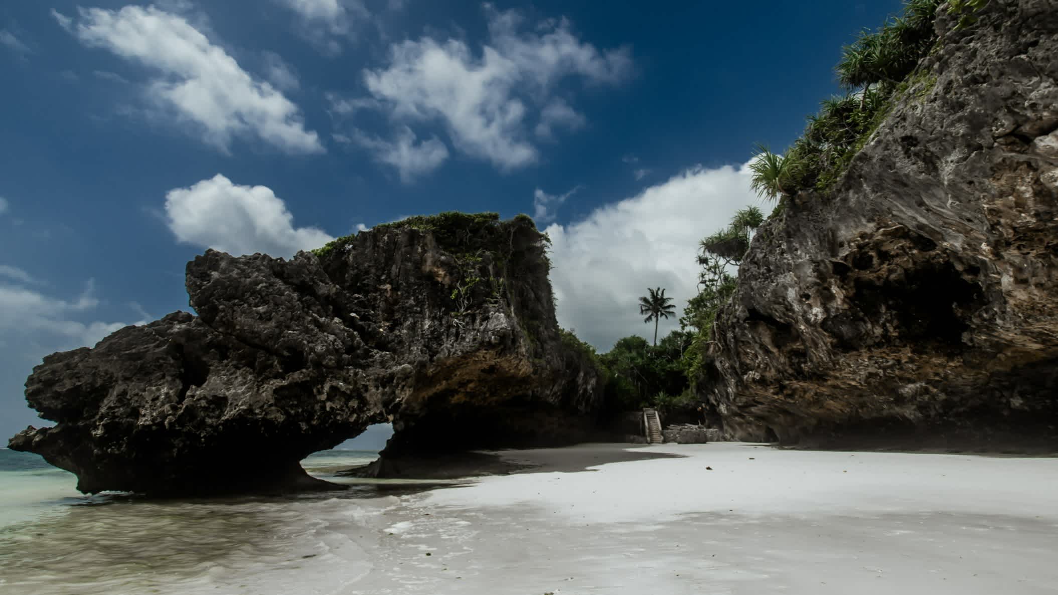 Vue d'une formation rocheuse sombre sur la plage de sable blanc de Mtende, Zanzibar.