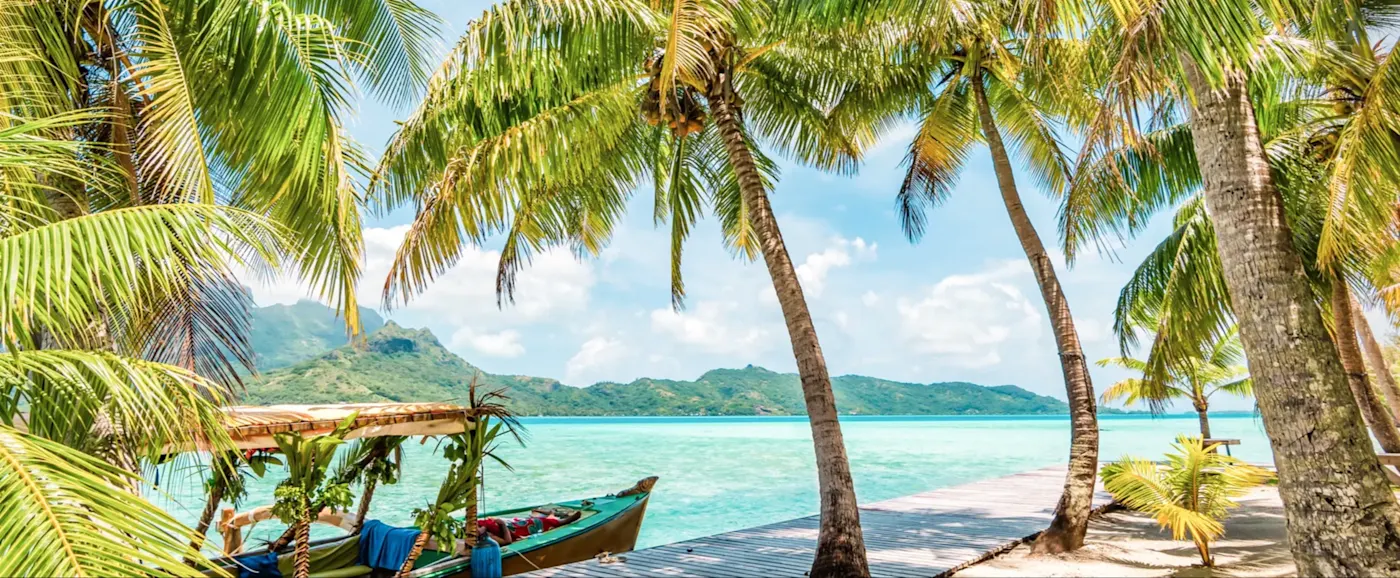 Palmiers sur la plage avec vue sur une eau turquoise. Bora Bora, Îles Sous-le-Vent, Polynésie française.