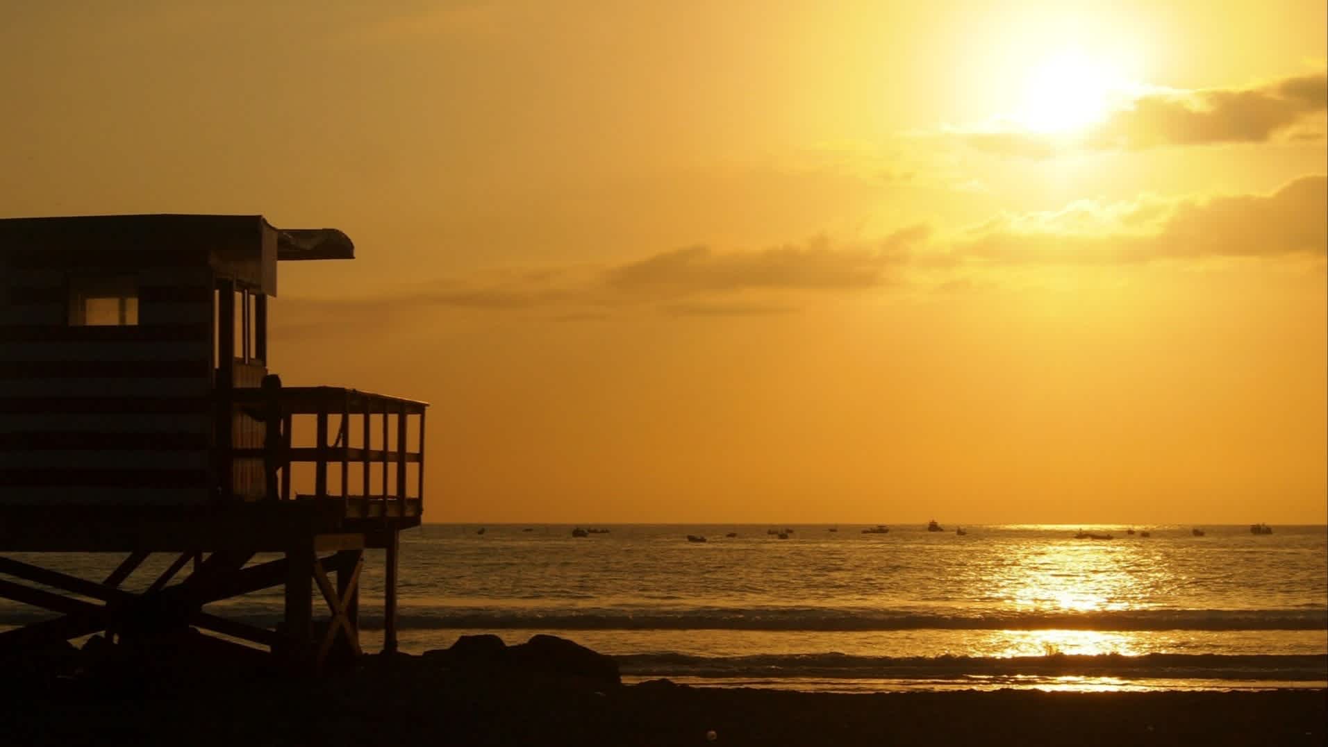 Der Strand von Puerto Cayo, Provinz Manabí, Ecuador bei Sonnendämmerung ind mit Blick auf ein Stelzenhaus.